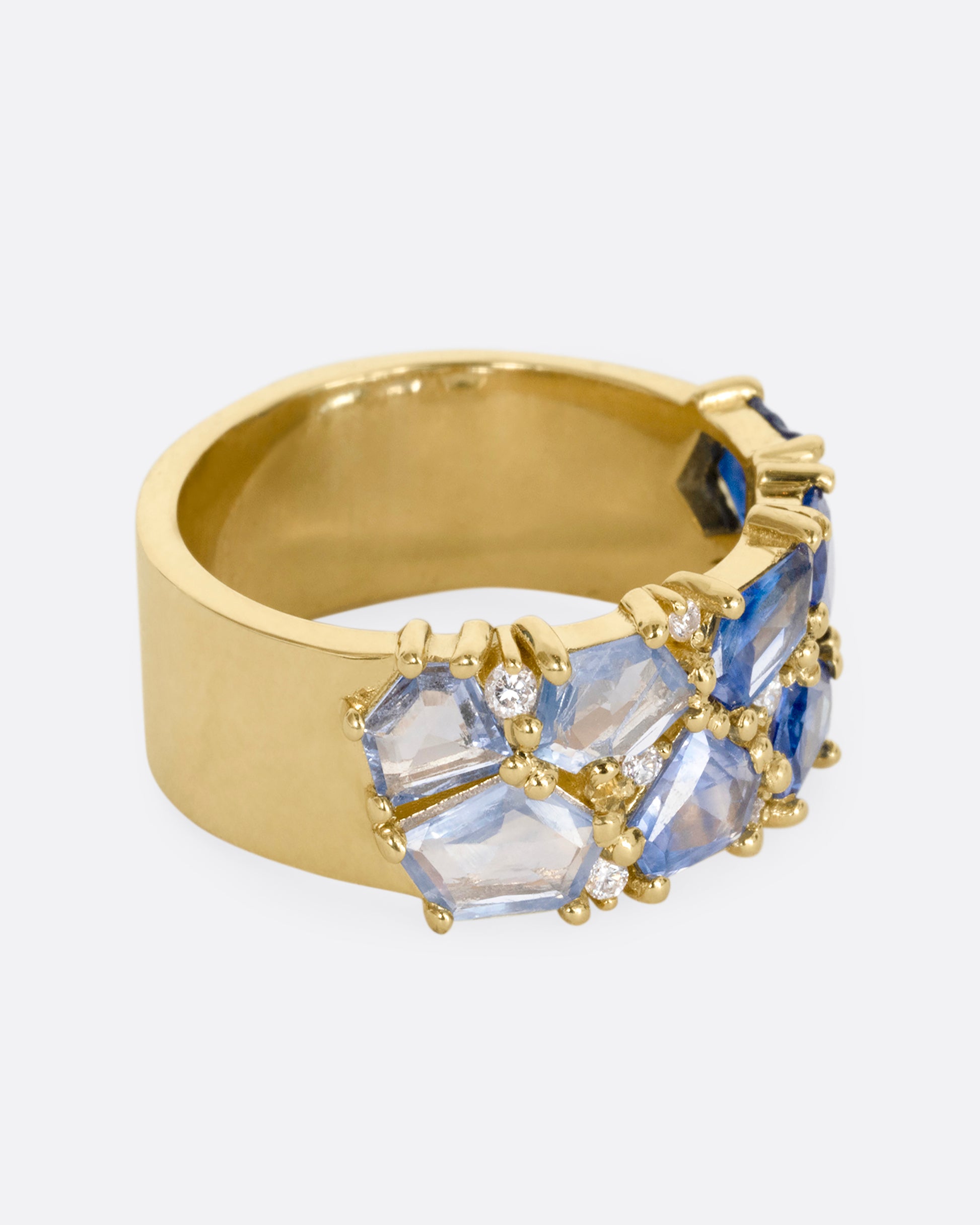 A yellow gold band with mosaic ombre blue sapphires and diamonds. Shown from the side.