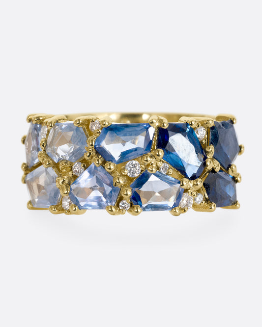 A yellow gold band with mosaic ombre blue sapphires and diamonds. Shown from the front.