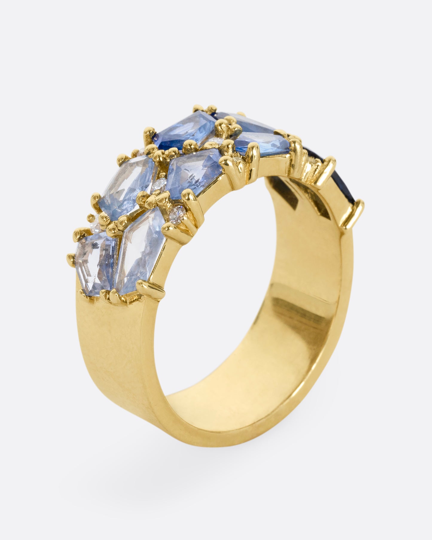 A yellow gold band with mosaic ombre blue sapphires and diamonds. Shown standing up from the side.