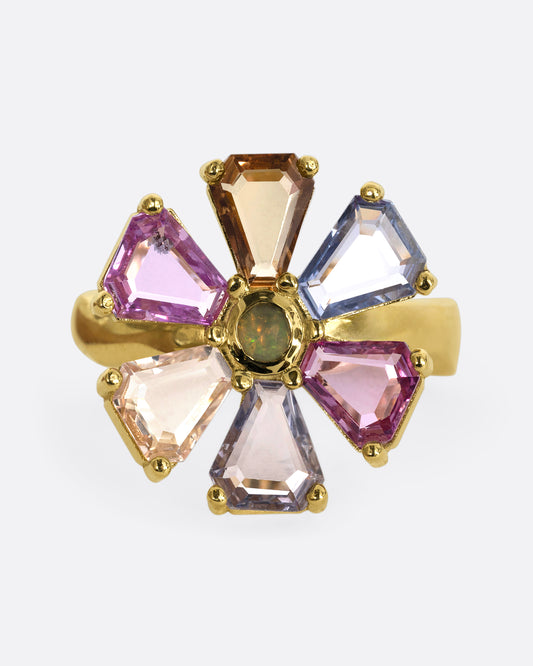 A yellow gold ring with a spinning flower made of multicolor sapphires. Shown from the front.