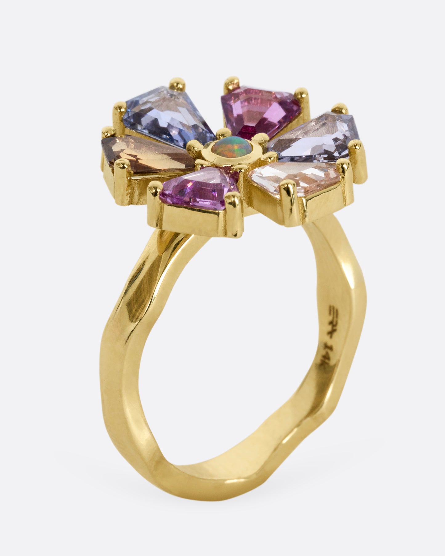 A yellow gold ring with a spinning flower made of multicolor sapphires. Shown from the side, standing up.