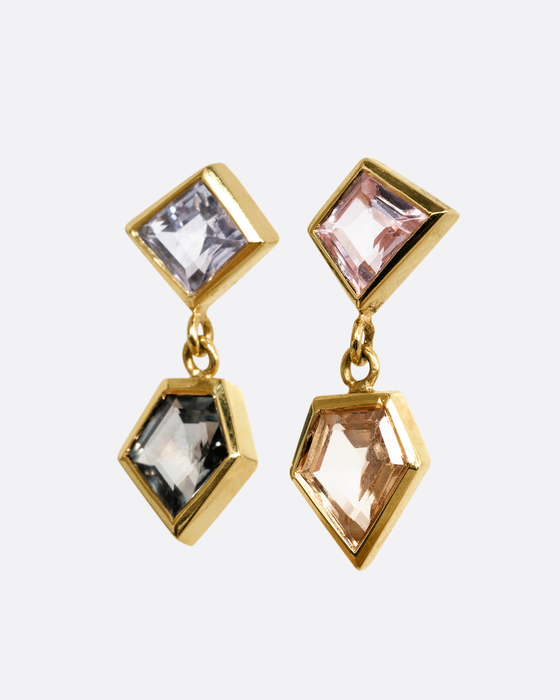 A pair of yellow gold drop earrings with trapezoid multicolor sapphires. Shown from the side.