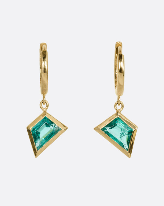 A yellow gold pair of hoop earrings with trapezoid emerald dangles. Shown from the front.