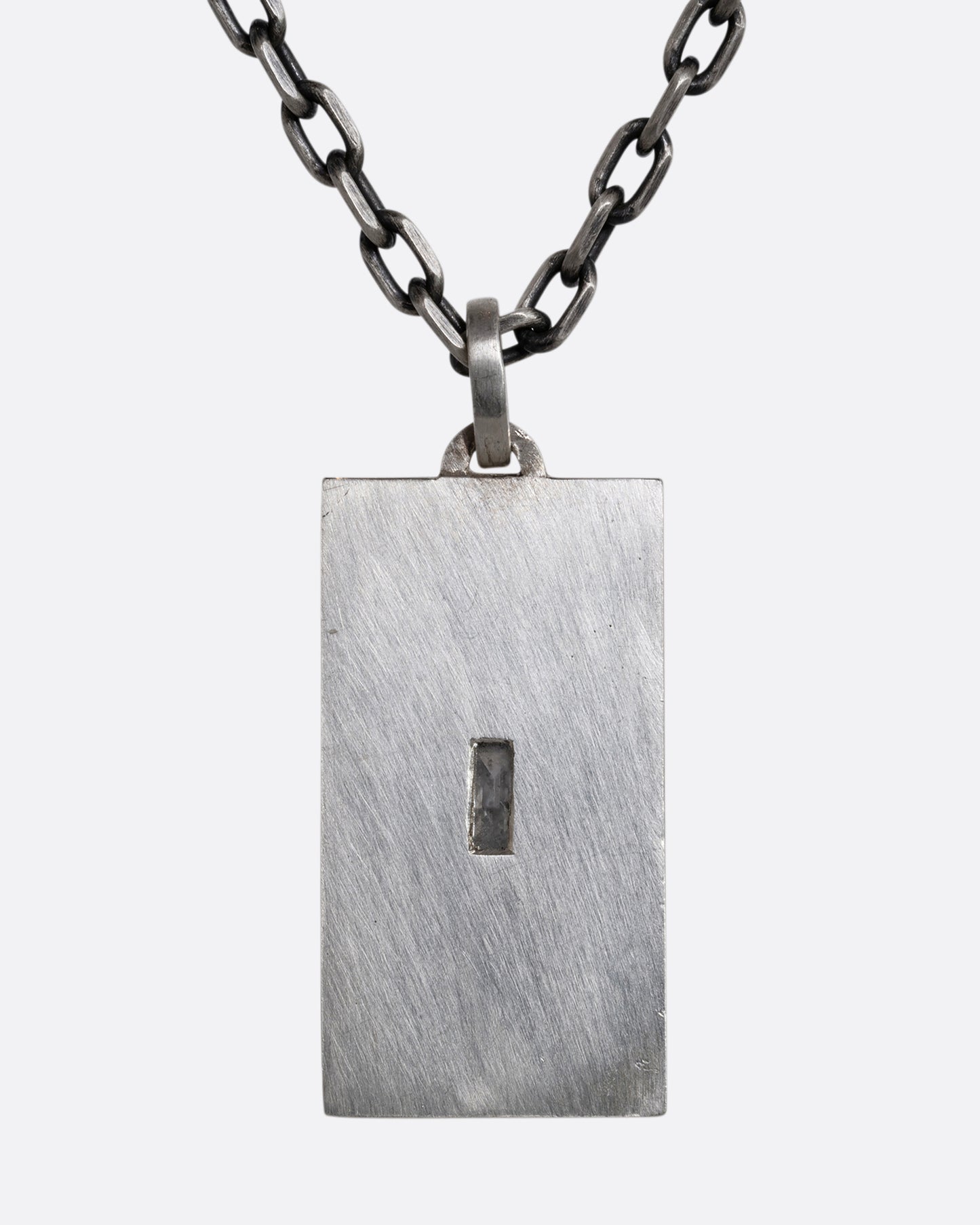 A sterling silver necklace with a rectangular pendant depicting two skeletons and a diamond at the center. Shown from the back.