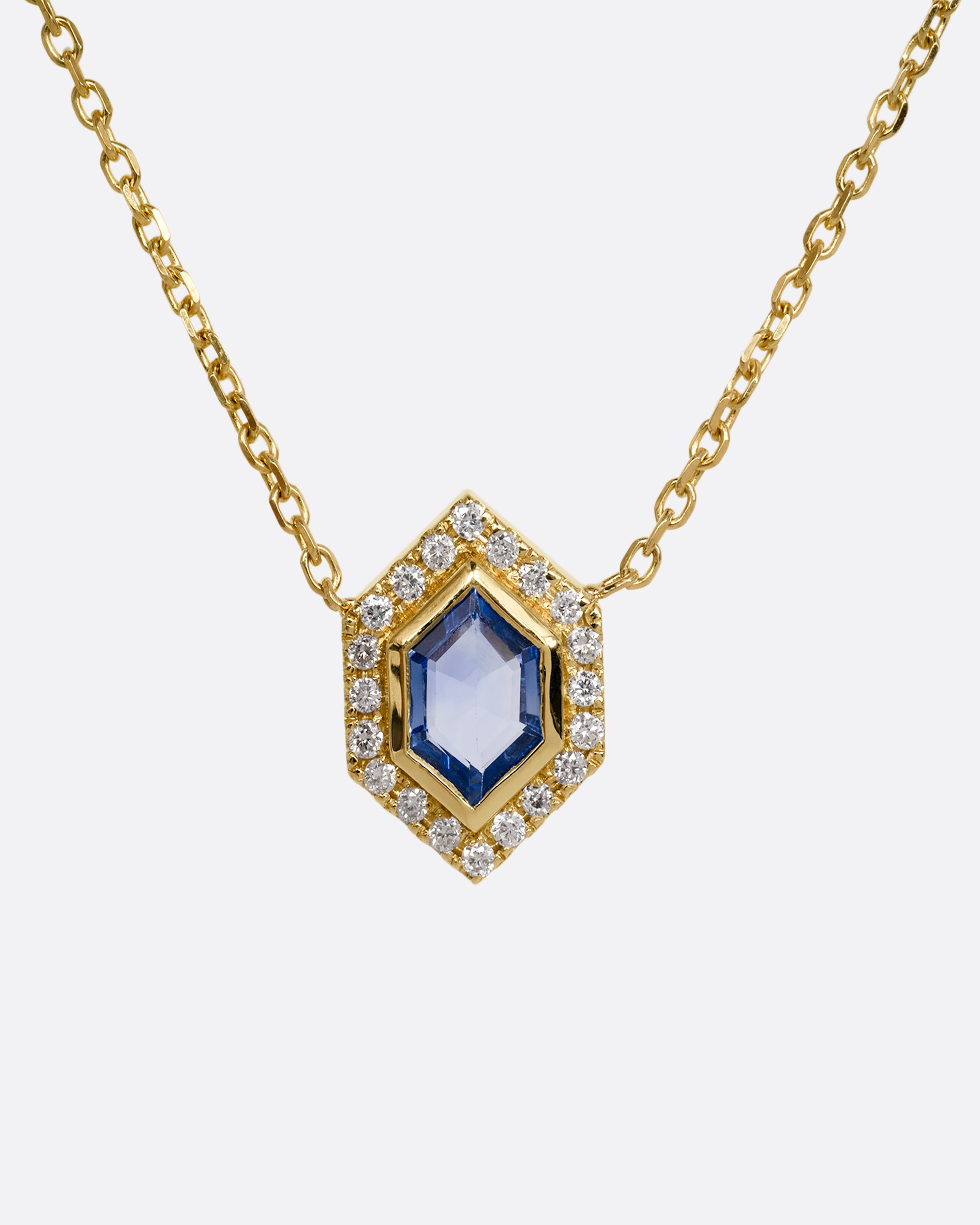 A yellow gold necklace with a hexagon shaped pendant containing a  blue sapphire and diamonds. Shown from the front.