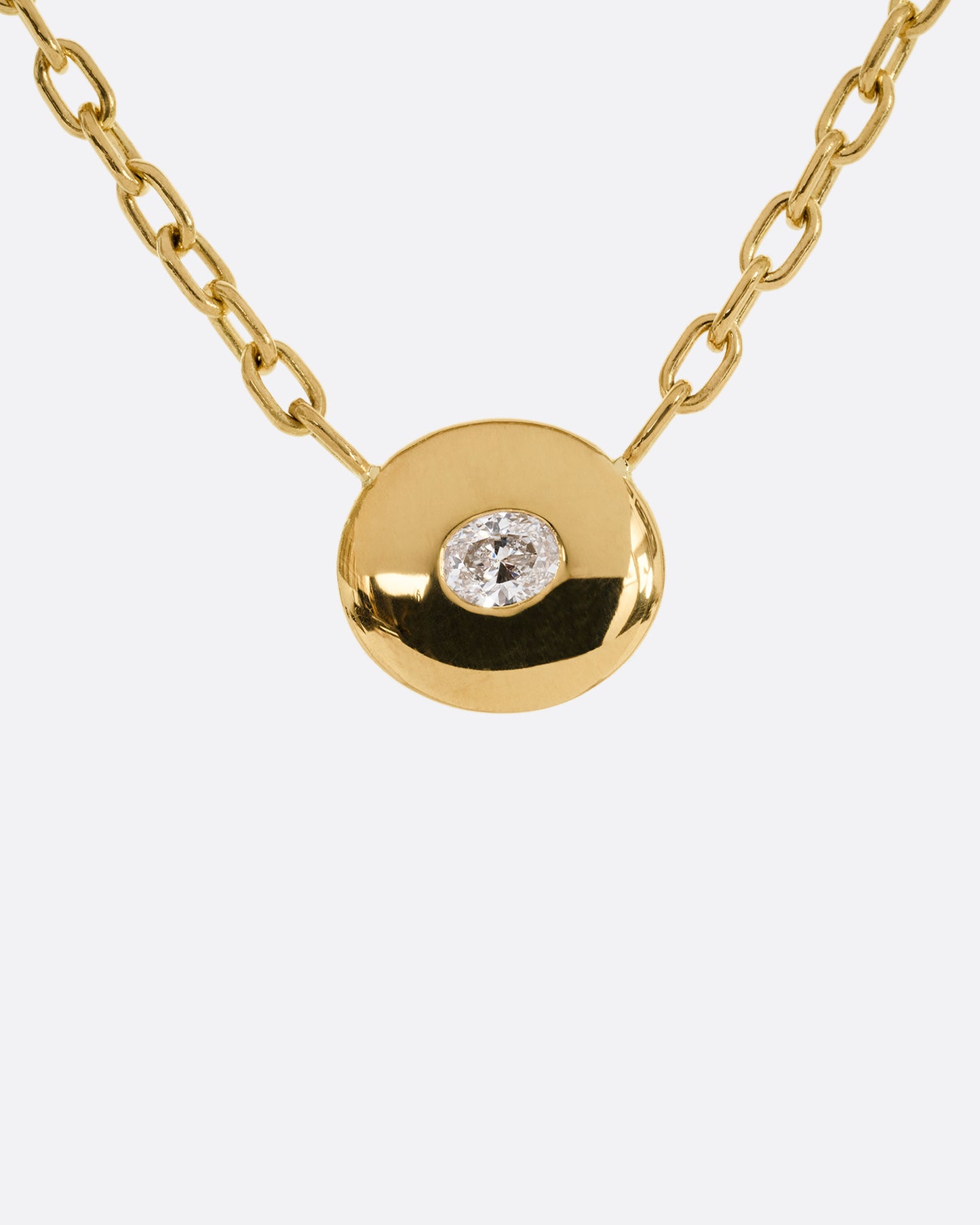 A yellow gold oval pendant necklace with an oval diamond and cable chain. Shown from the front.