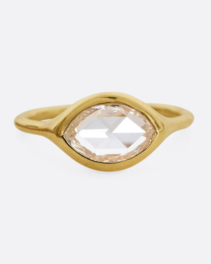 A yellow gold ring with a horizontal rose cut marquise diamond. Shown from the front.