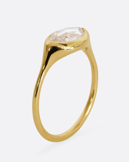 A yellow gold ring with a horizontal rose cut marquise diamond. Shown standing up from the side.