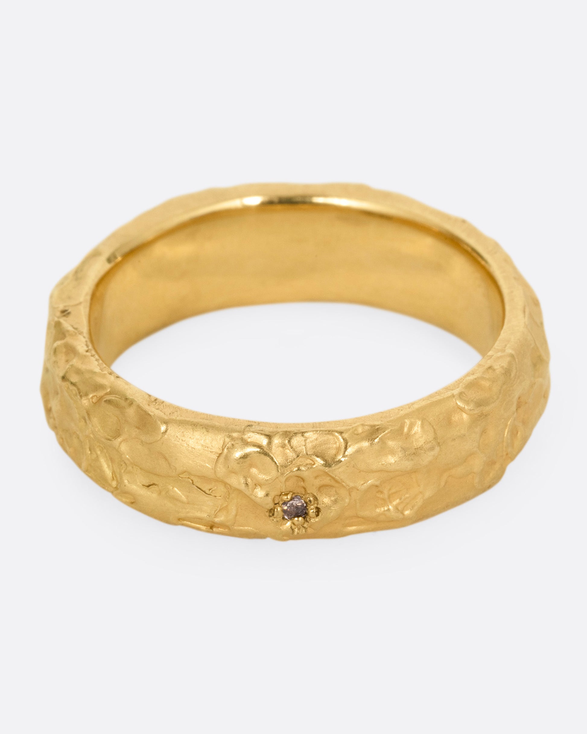 A textured yellow gold band with a brown diamond, shown from the front from above.