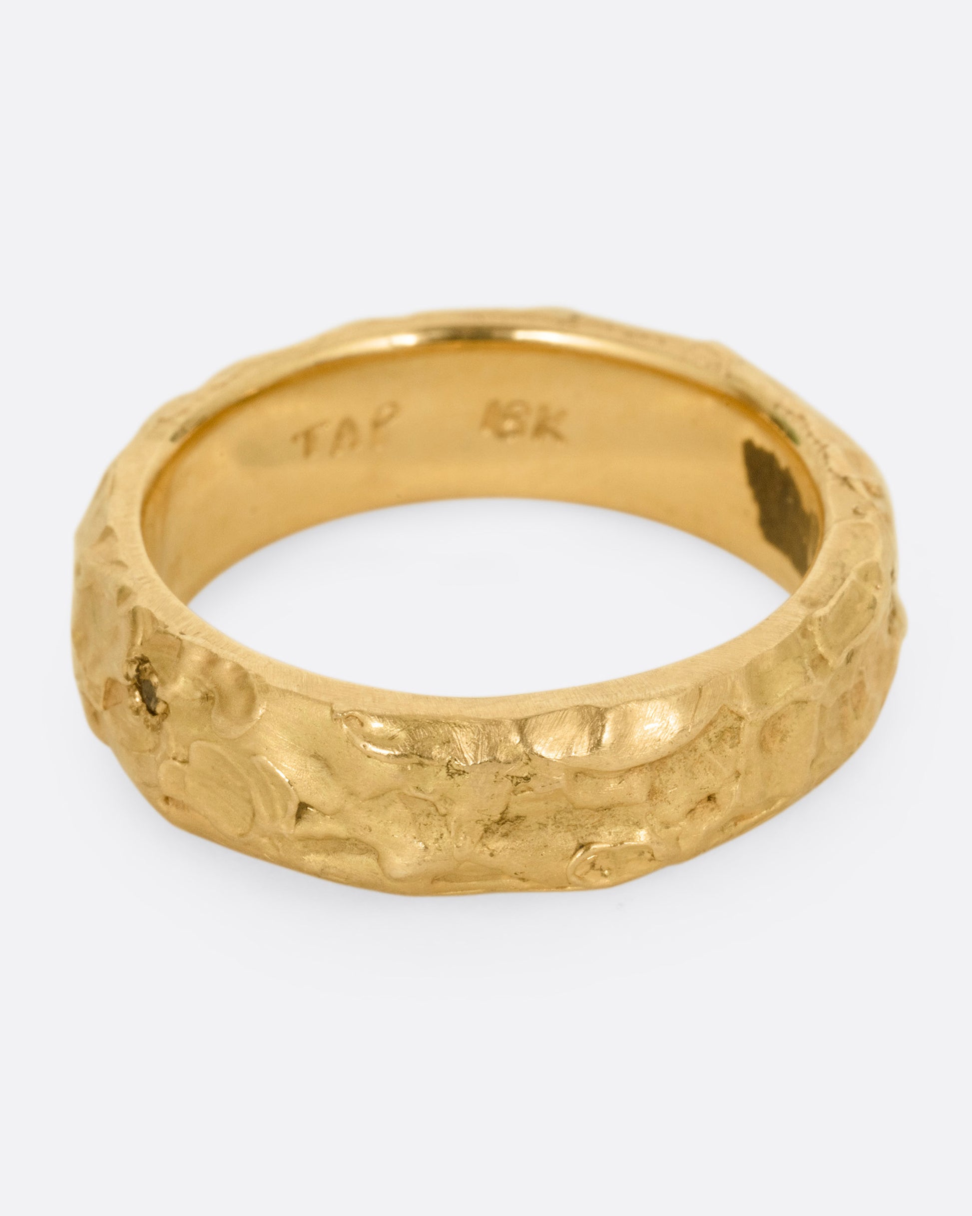 A textured yellow gold band with a brown diamond, shown from the side.