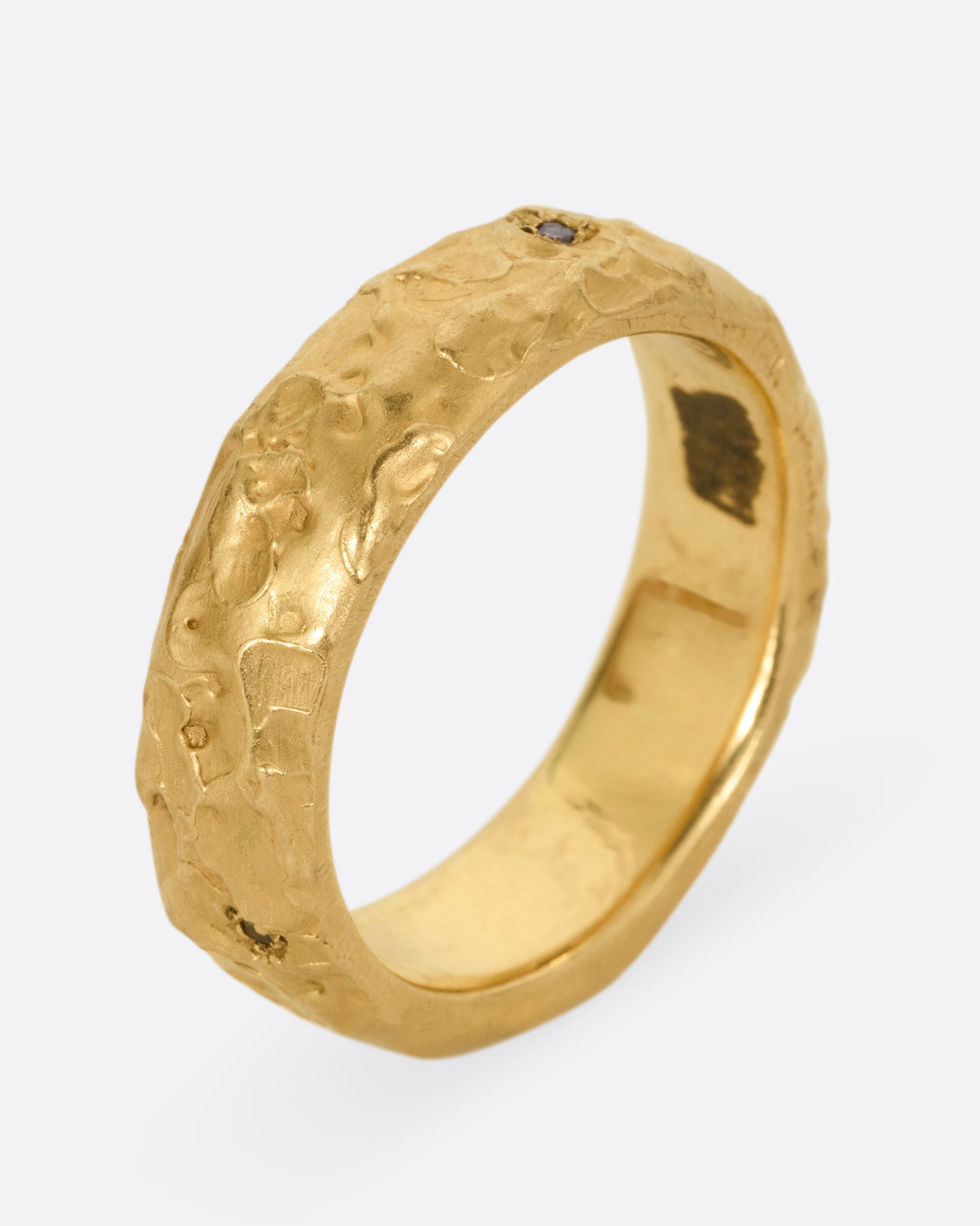 A textured yellow gold band with a brown diamond, shown from the side standing up.