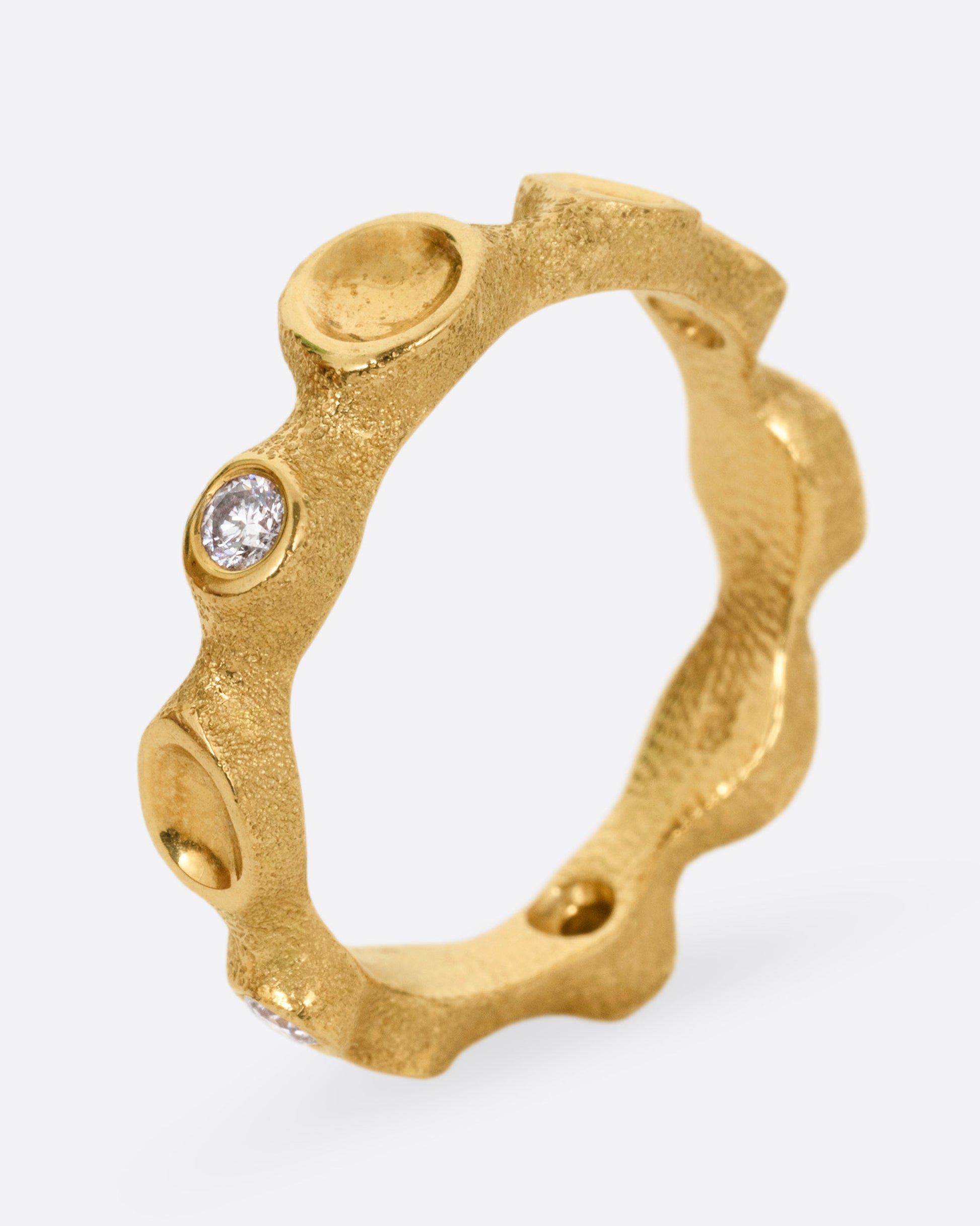 A yellow gold ring resembling a coral reef, with white diamonds, shown from the side standing up.