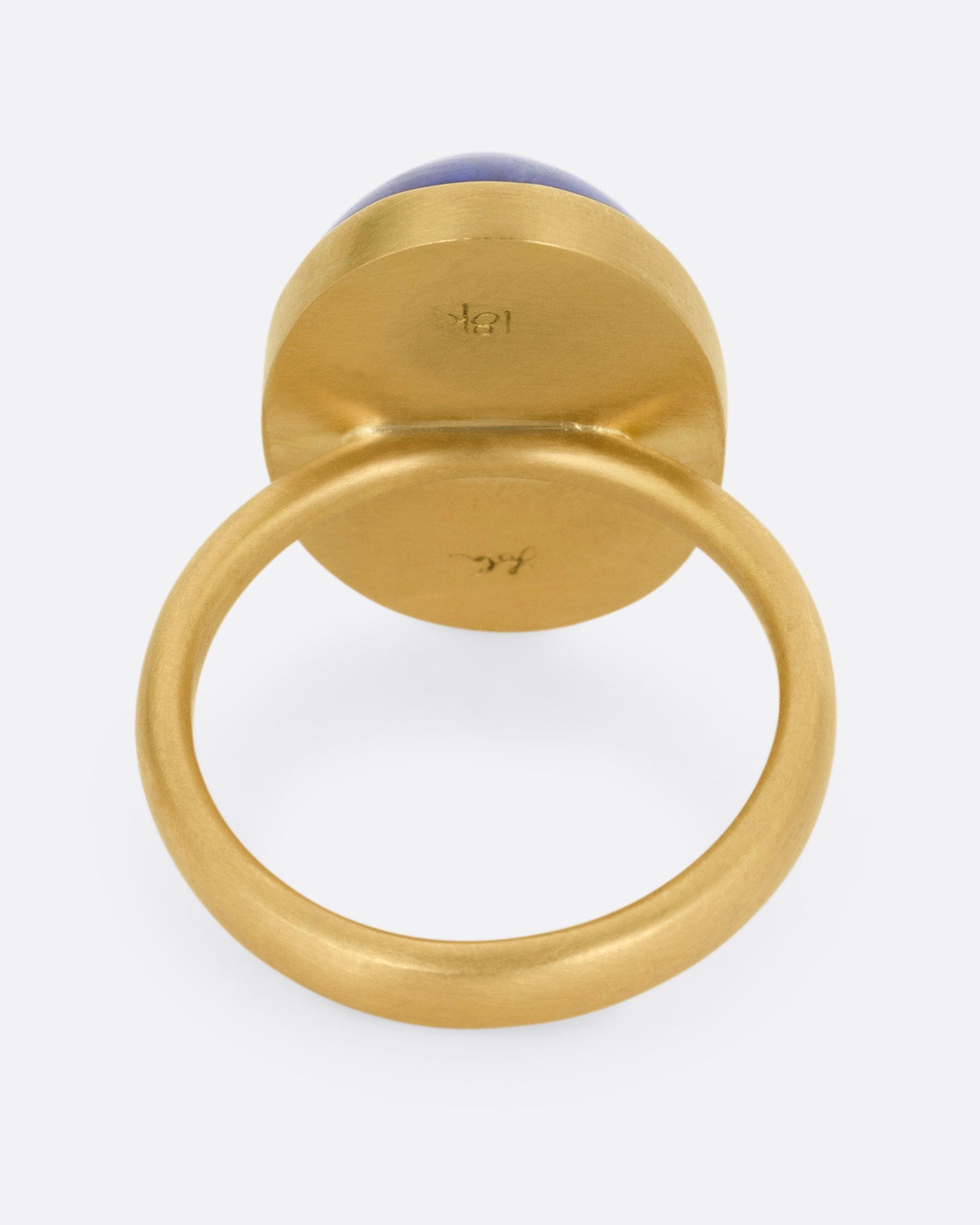 A yellow gold ring with a large blue oval tanzanite, shown from the back.