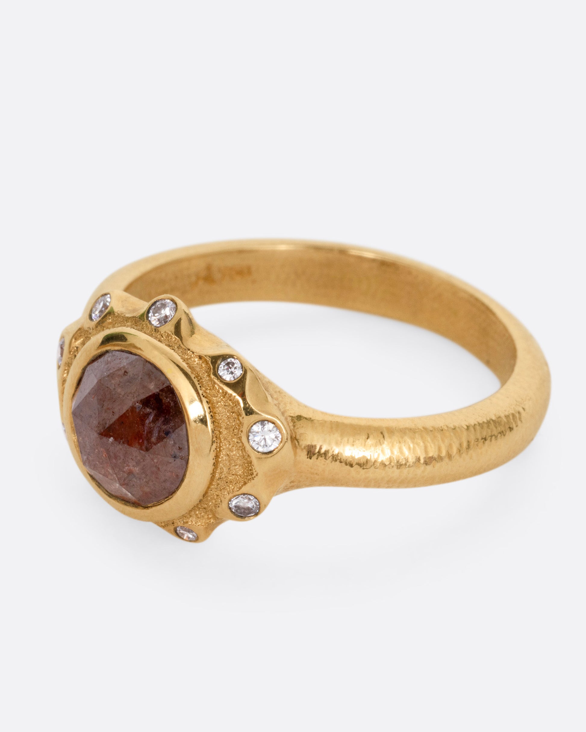 A yellow gold ring with a brown diamond and white diamond accents, shown from the side.