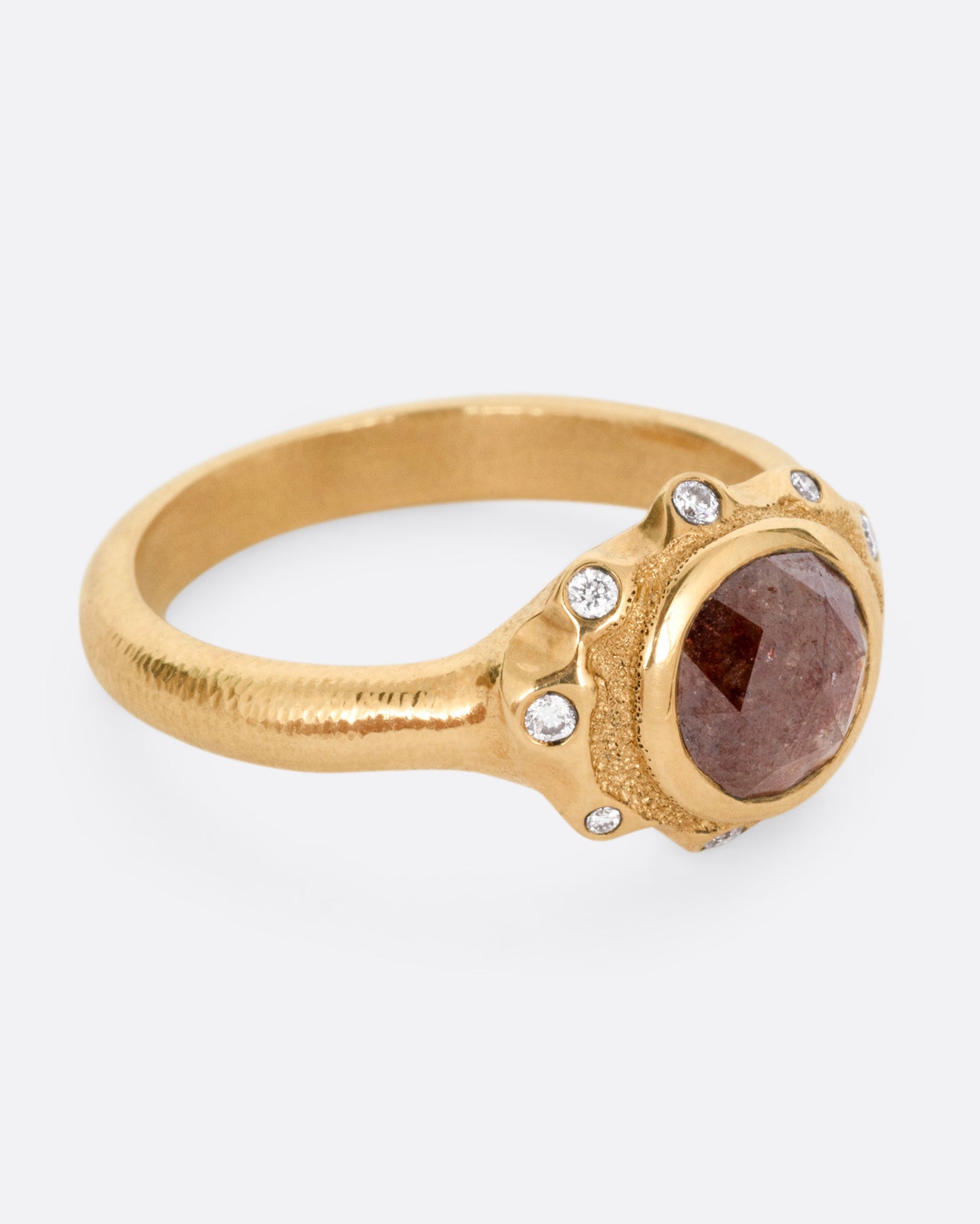 A yellow gold ring with a brown diamond and white diamond accents, shown from the side.