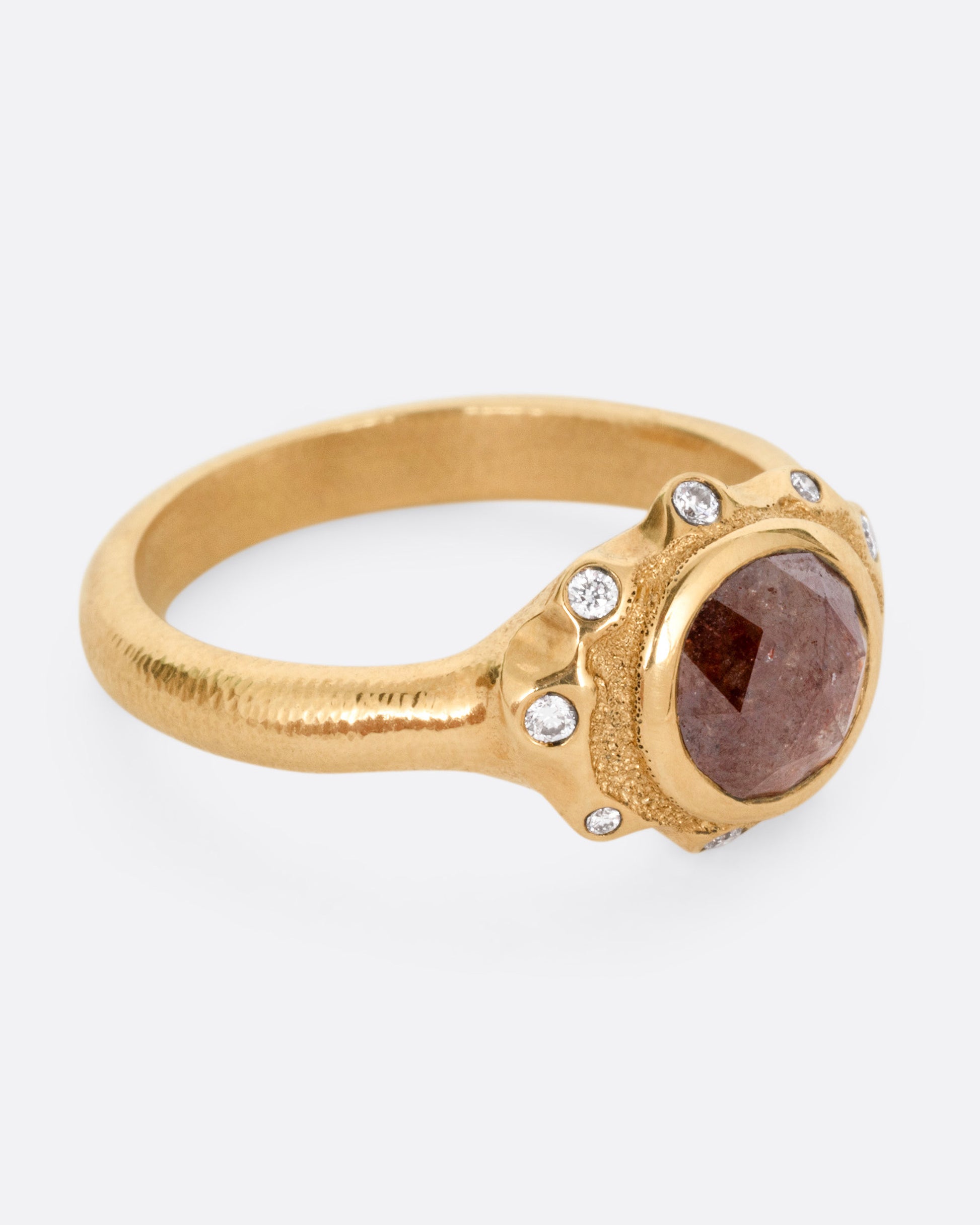 A yellow gold ring with a brown diamond and white diamond accents, shown from the side.