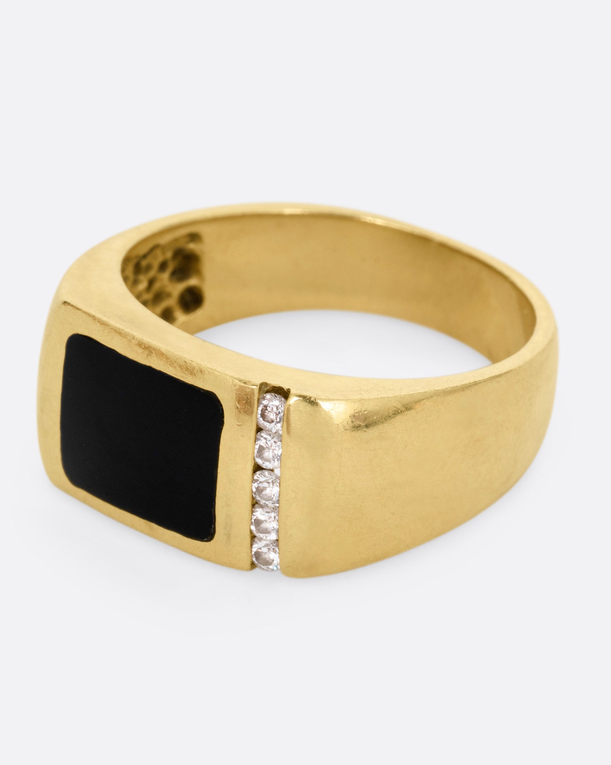 A yellow gold ring with a column of diamonds and a black enamel rectangle, shown from the side.