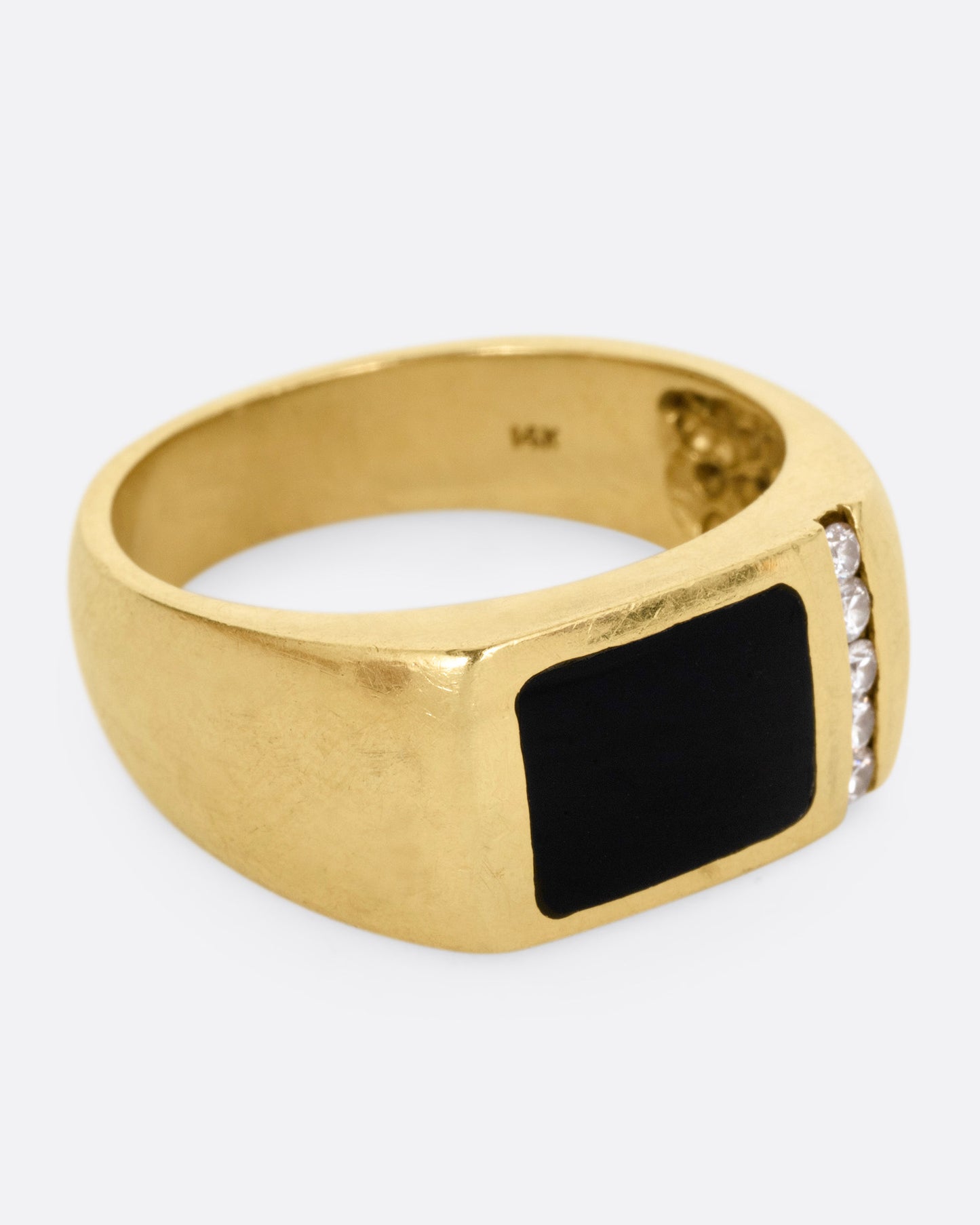 A yellow gold ring with a column of diamonds and a black enamel rectangle, shown from the side.