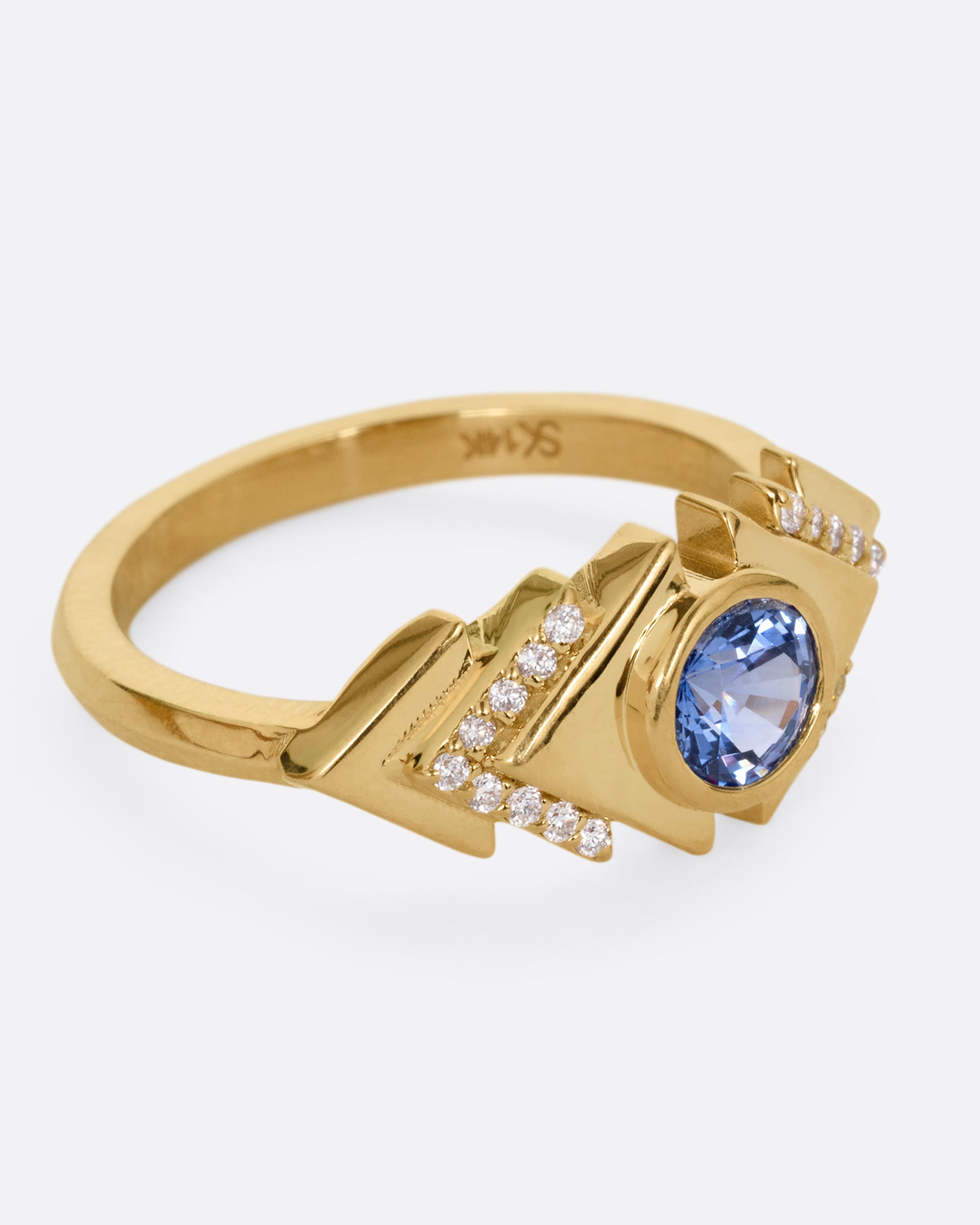 A yellow gold ring with a blue sapphire at the center of angular steps with diamond accents, shown from the side.