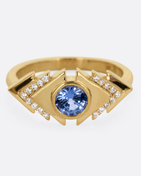 A yellow gold ring with a blue sapphire at the center of angular steps with diamond accents, shown from the front.