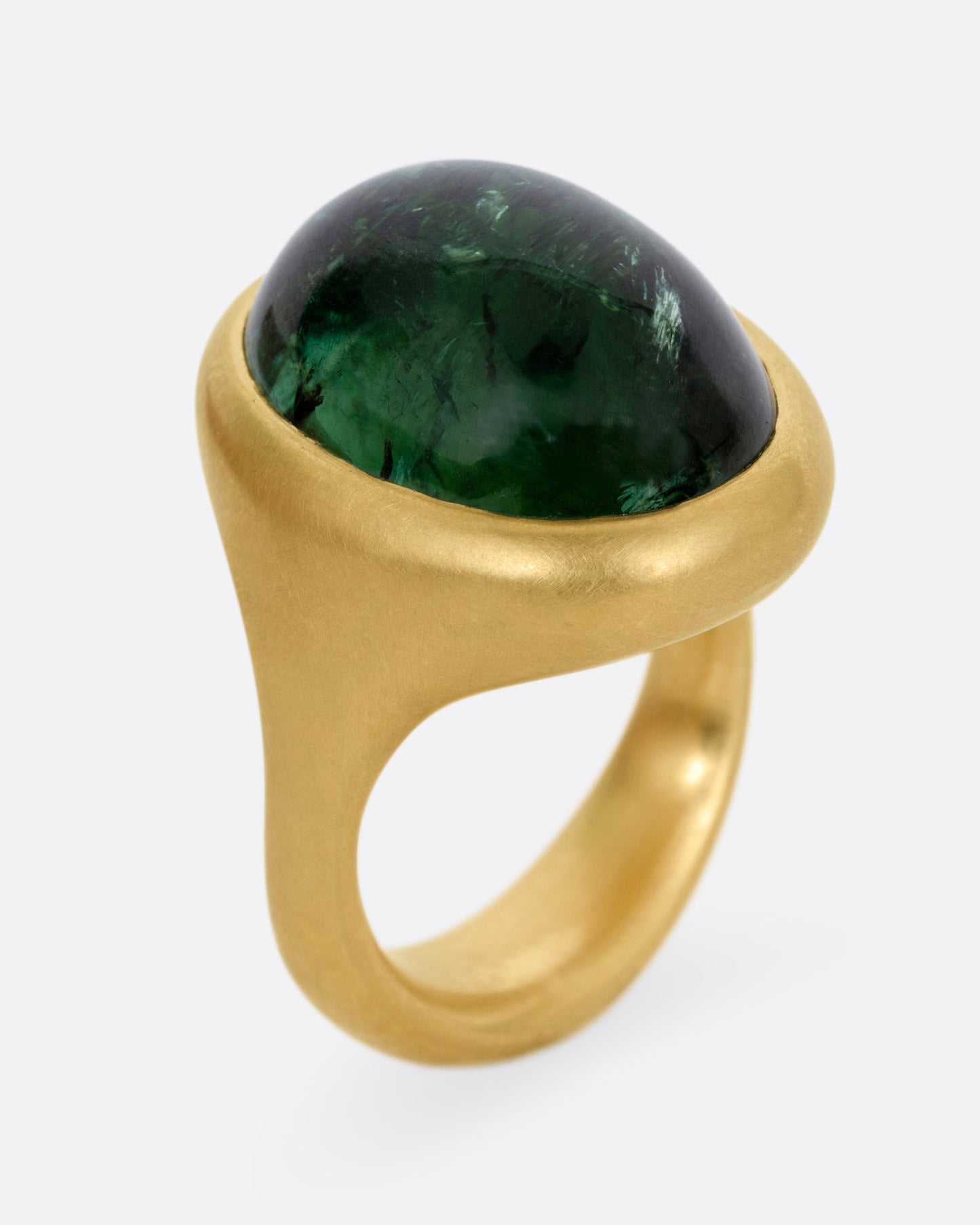 A yellow gold ring with a green tourmaline cabochon, shown from the side standing up.