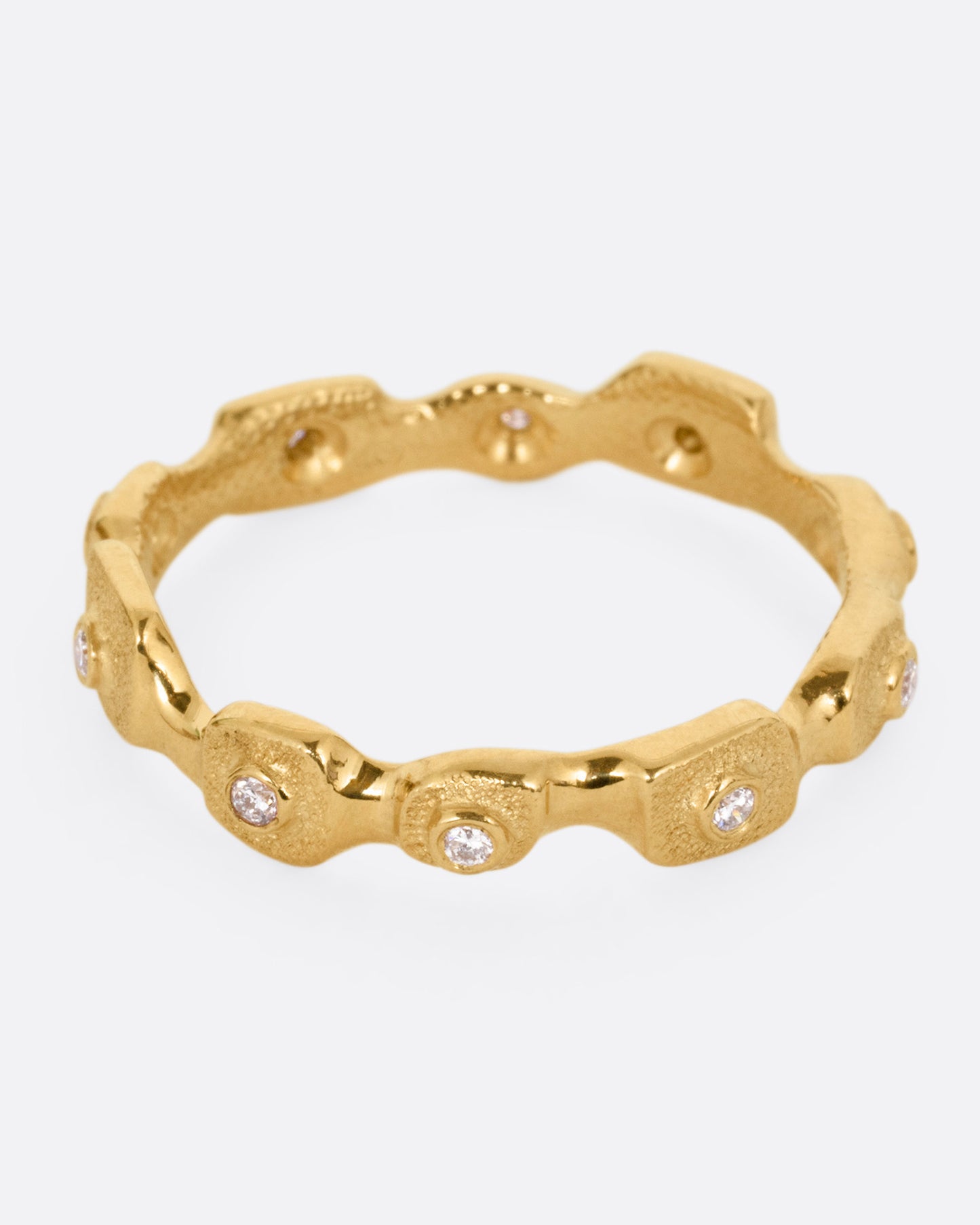 A yellow gold ring with stations of single diamonds, shown from the front.