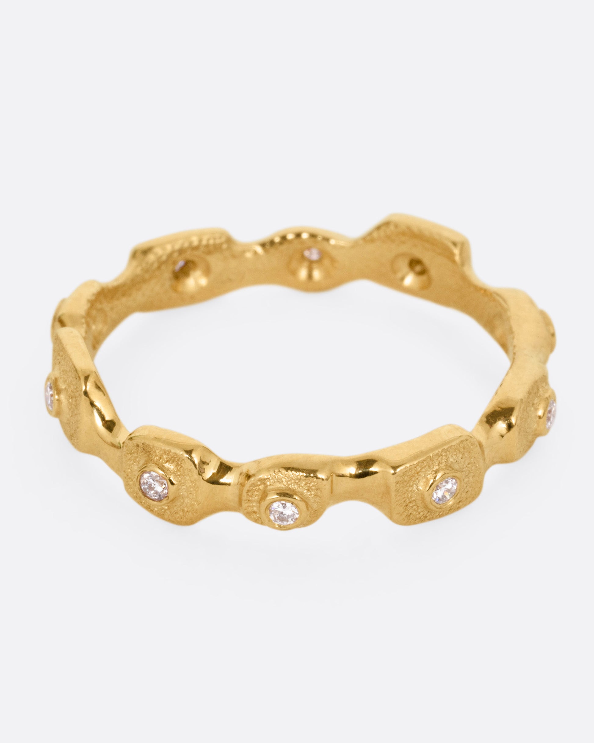 A yellow gold ring with stations of single diamonds, shown from the front.