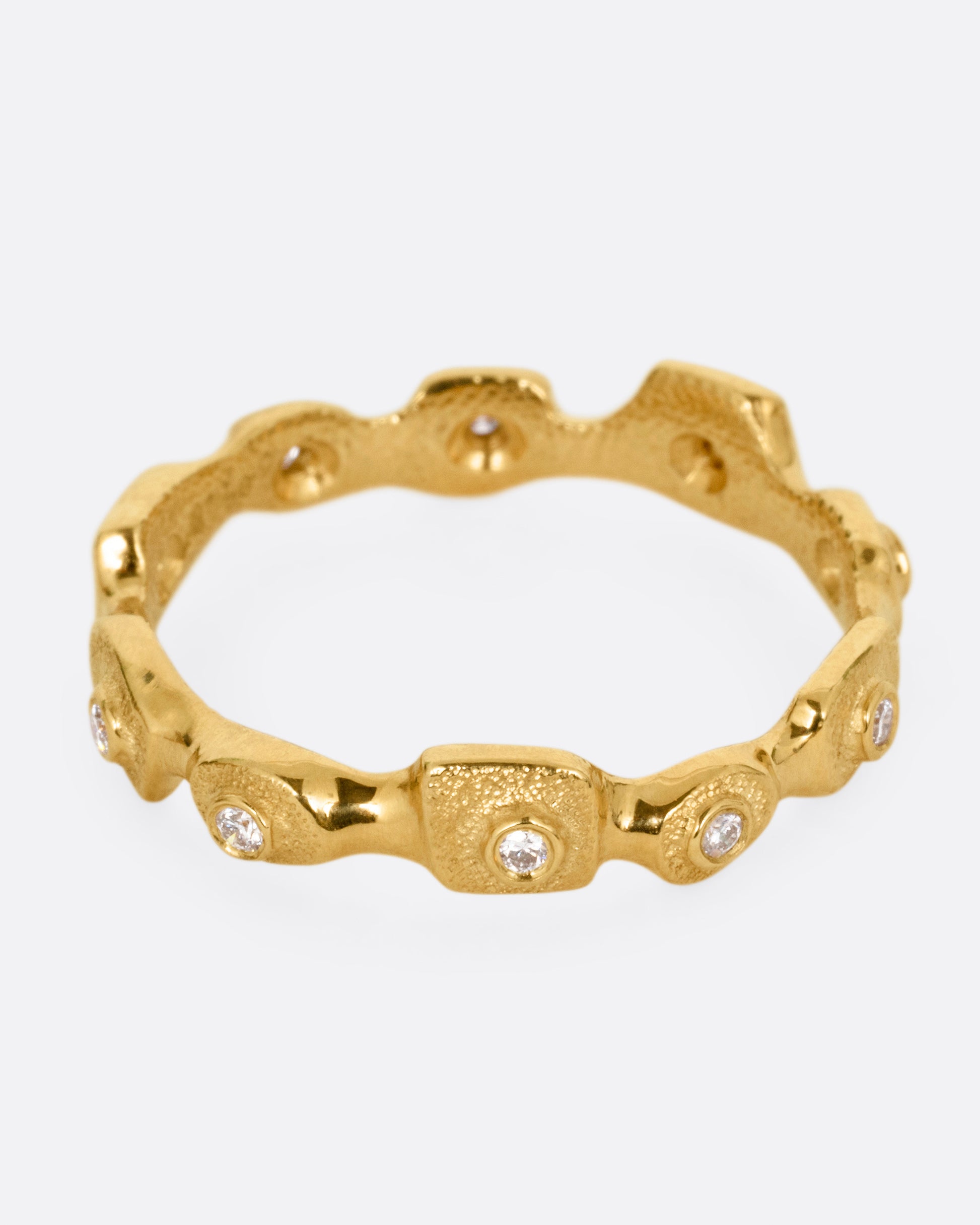 A yellow gold ring with stations of single diamonds, shown from the front.