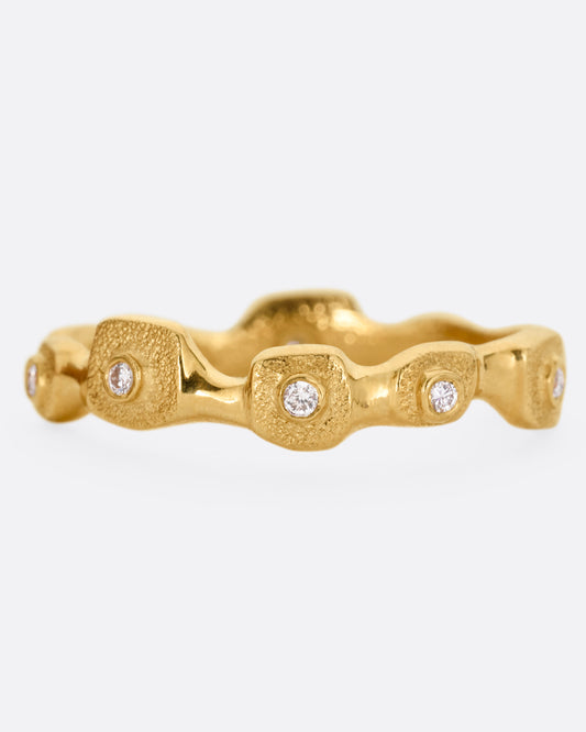 A yellow gold ring with stations of single diamonds, shown from the front.