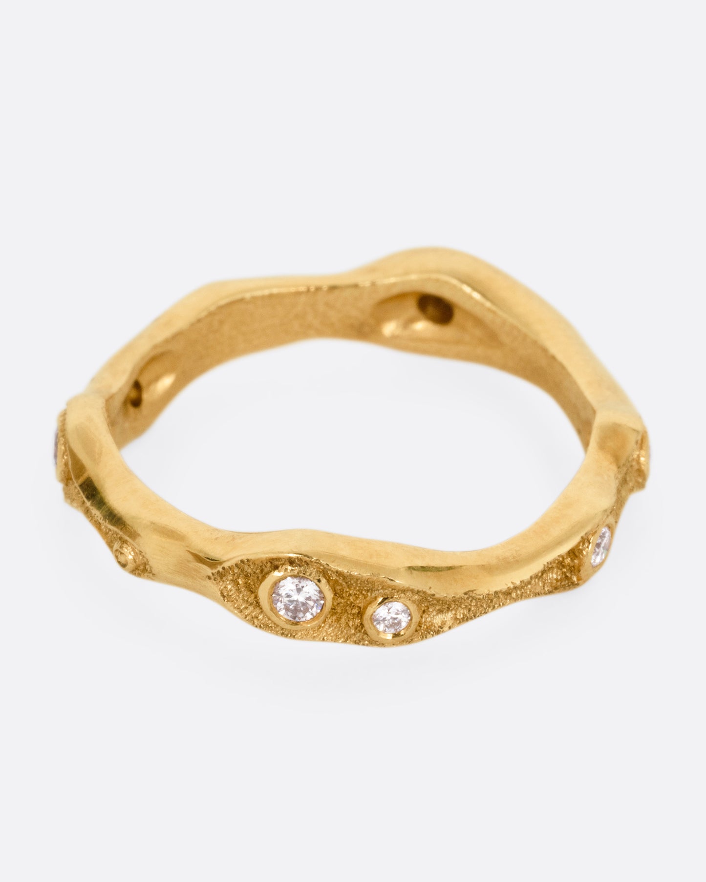 A textured yellow gold ring with white diamonds. Shown from the side.