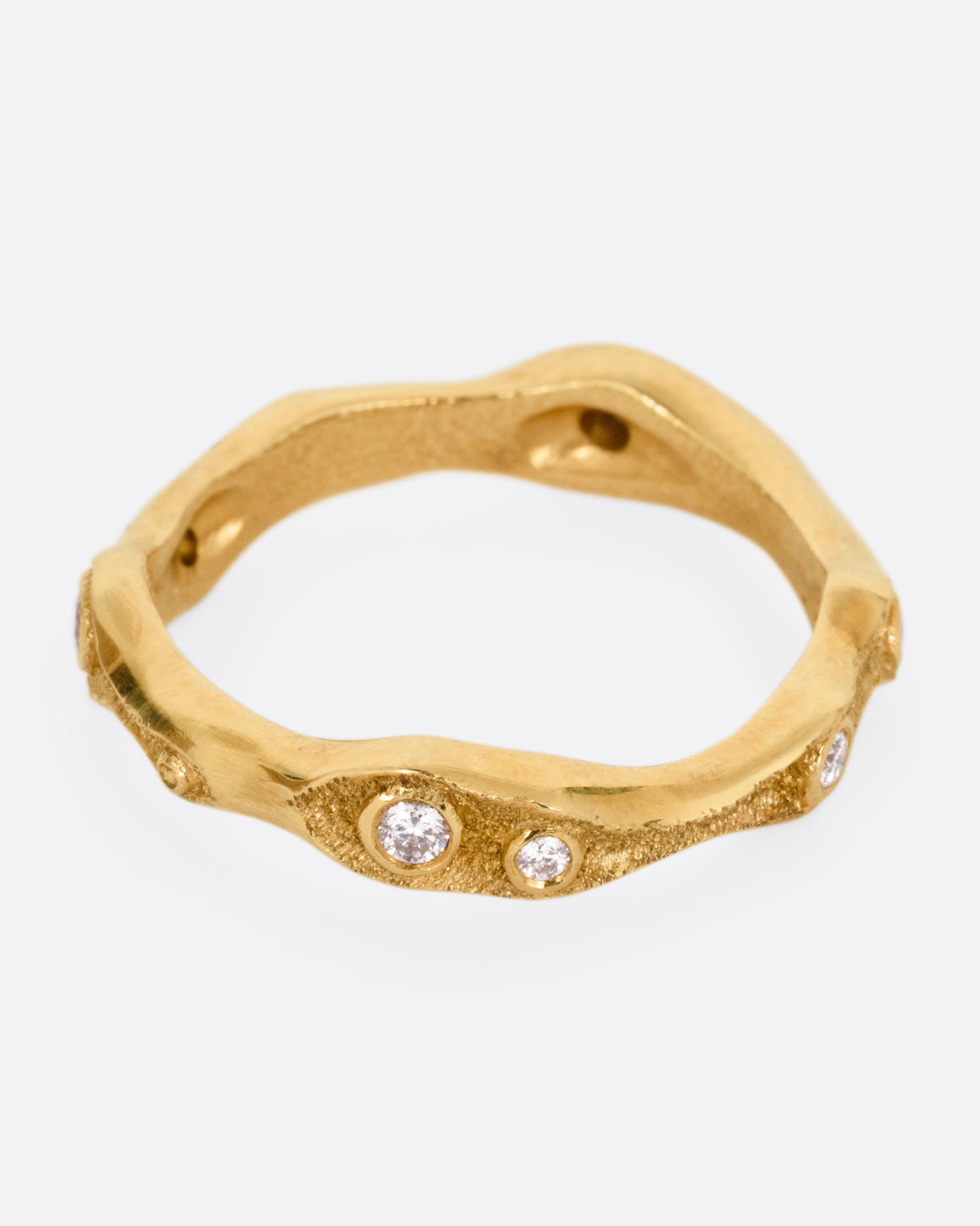 A textured yellow gold ring with white diamonds. Shown from the side.