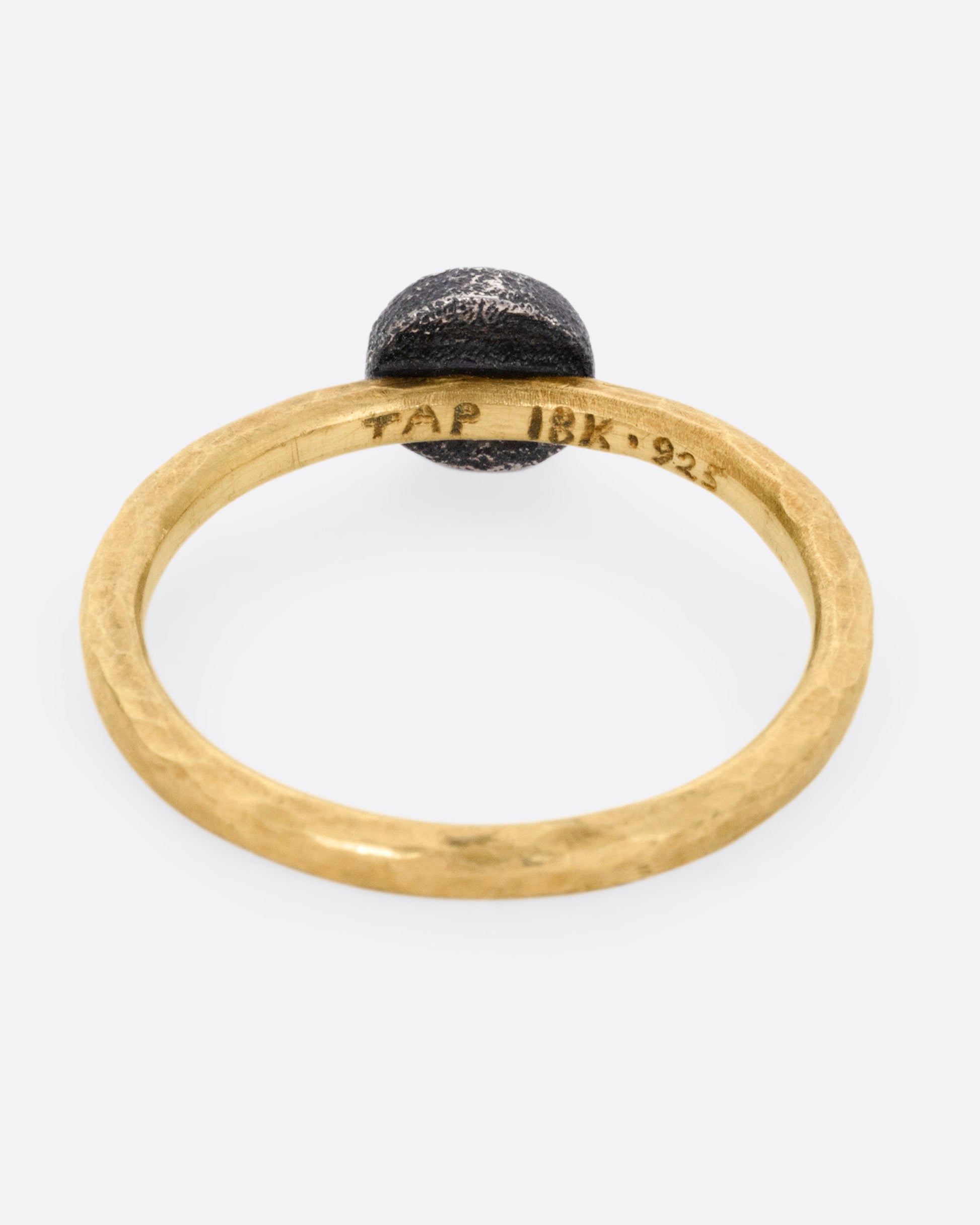 A yellow gold ring with a darkened sterling bezel and a yellow diamond, shown from the back.