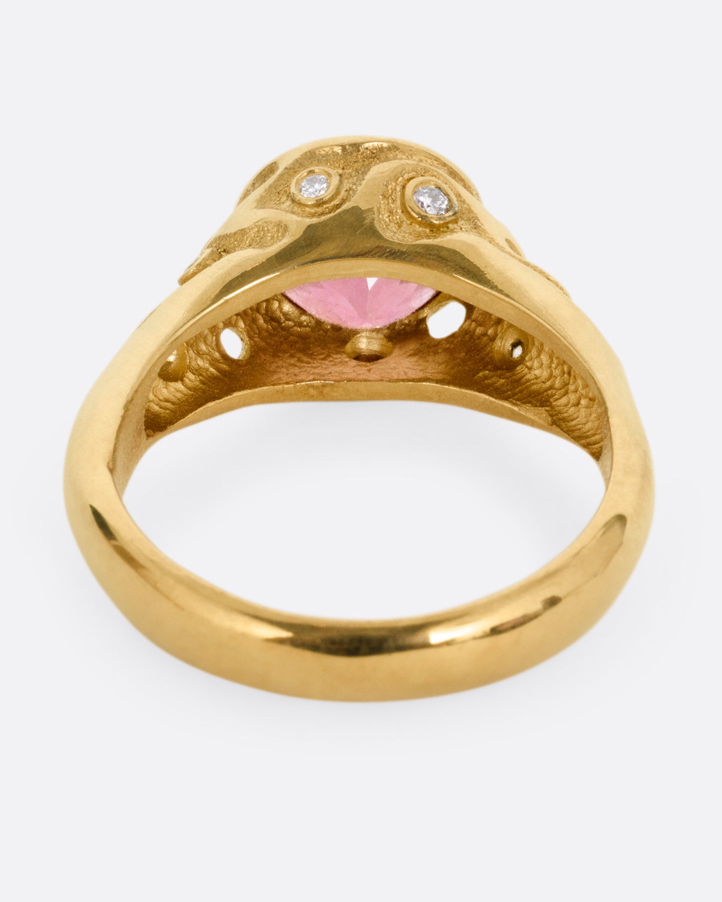 A yellow gold ring with a rose cut pink tourmaline and diamond freckled shoulders, shown from the back.