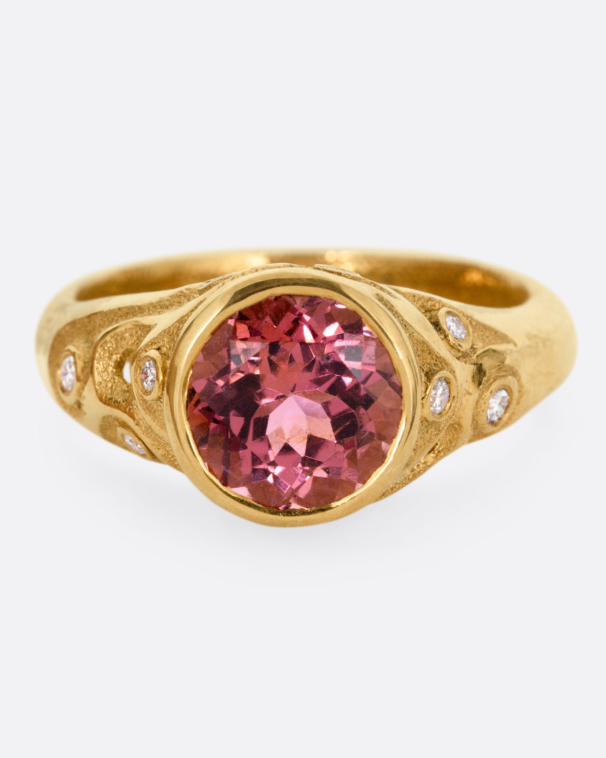 A yellow gold ring with a rose cut pink tourmaline and diamond freckled shoulders, shown from the front.