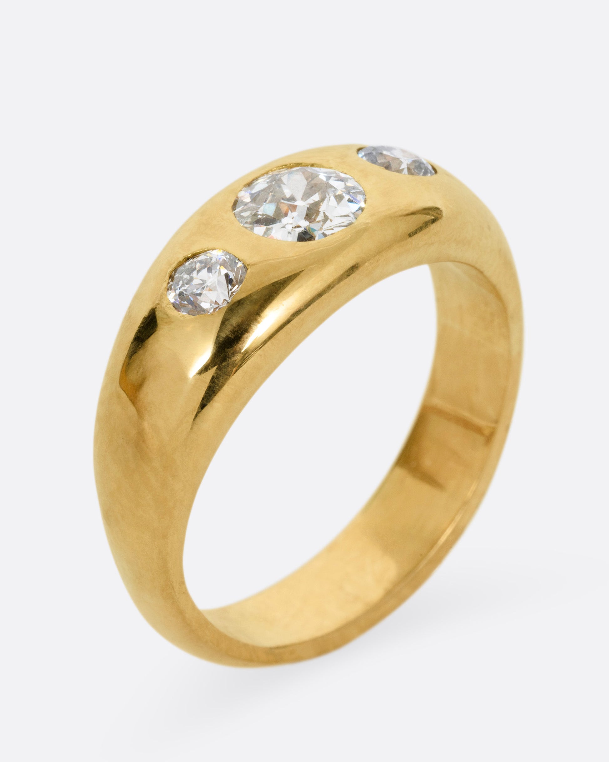 A yellow gold ring with three diamonds, shown from the side standing up.
