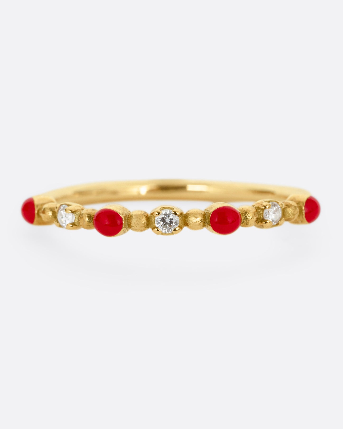 A yellow gold ring with three white diamonds and four red resin droplets, shown from the front.