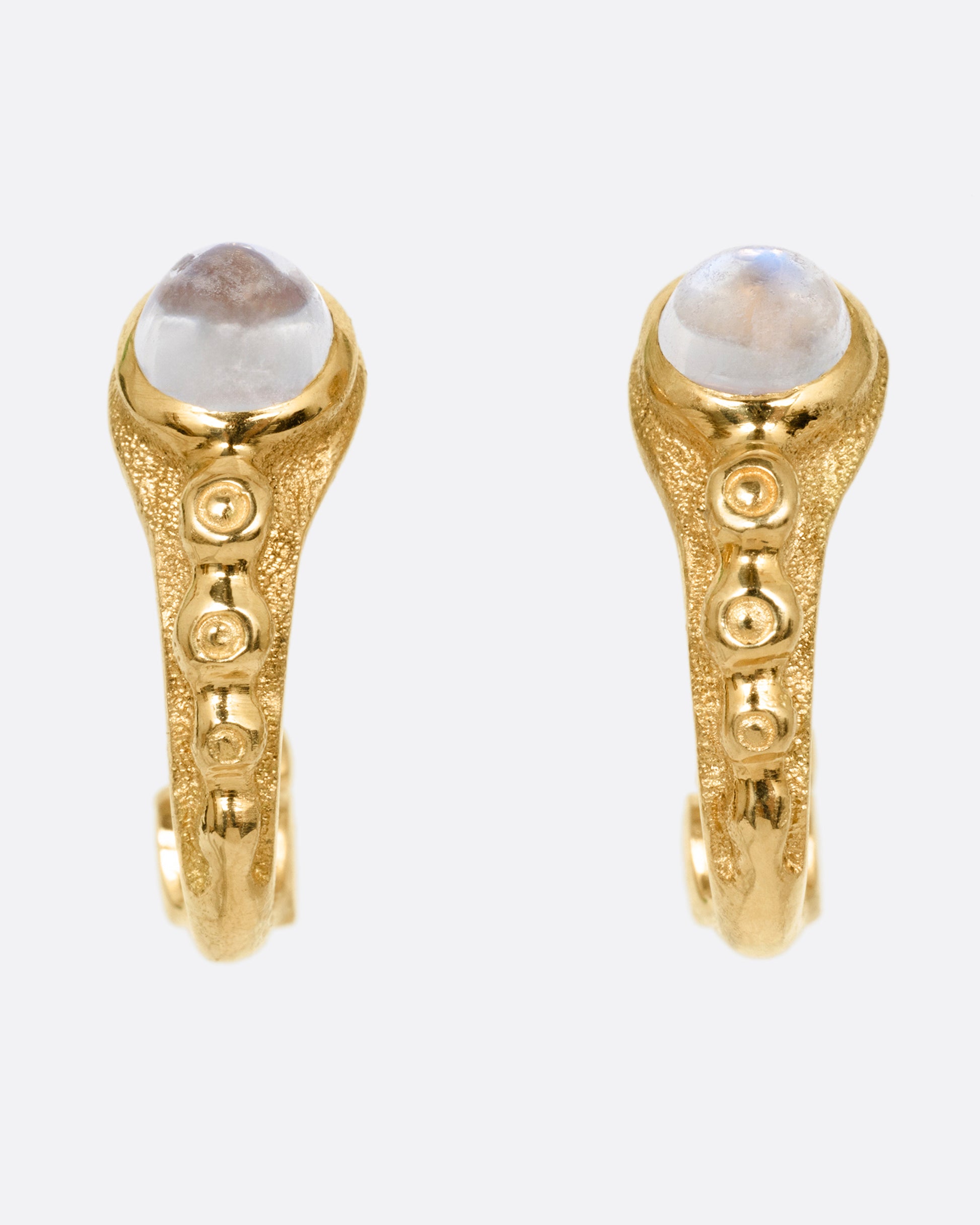 A pair of yellow gold hoop earrings with granulation and moonstones in each. Shown from the front.