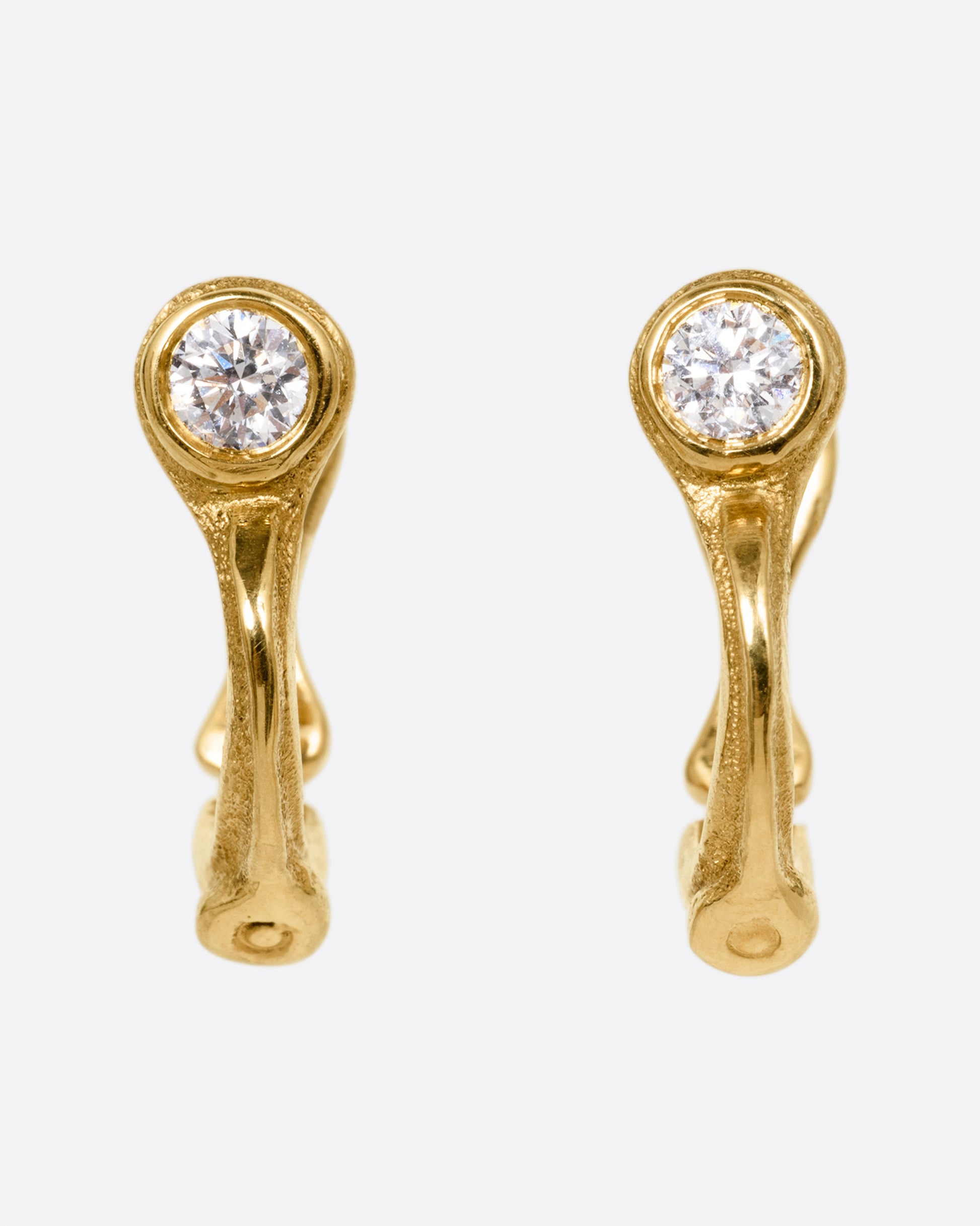 A pair of yellow gold hoop earrings with brilliant cut diamonds, shown from the front.