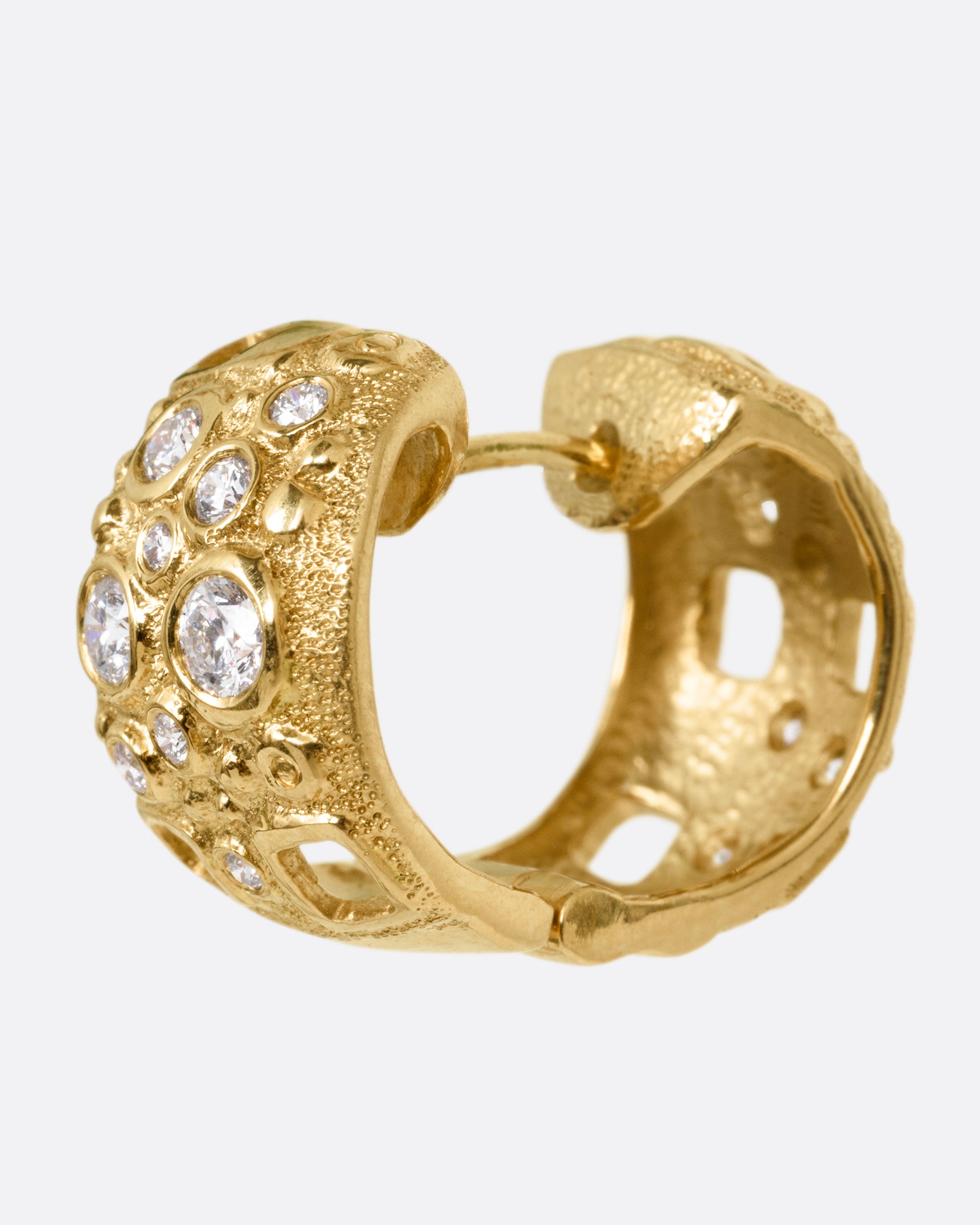 A wide yellow gold huggie hoop with diamonds of varying sizes and small rectangular cutouts, shown from the side.