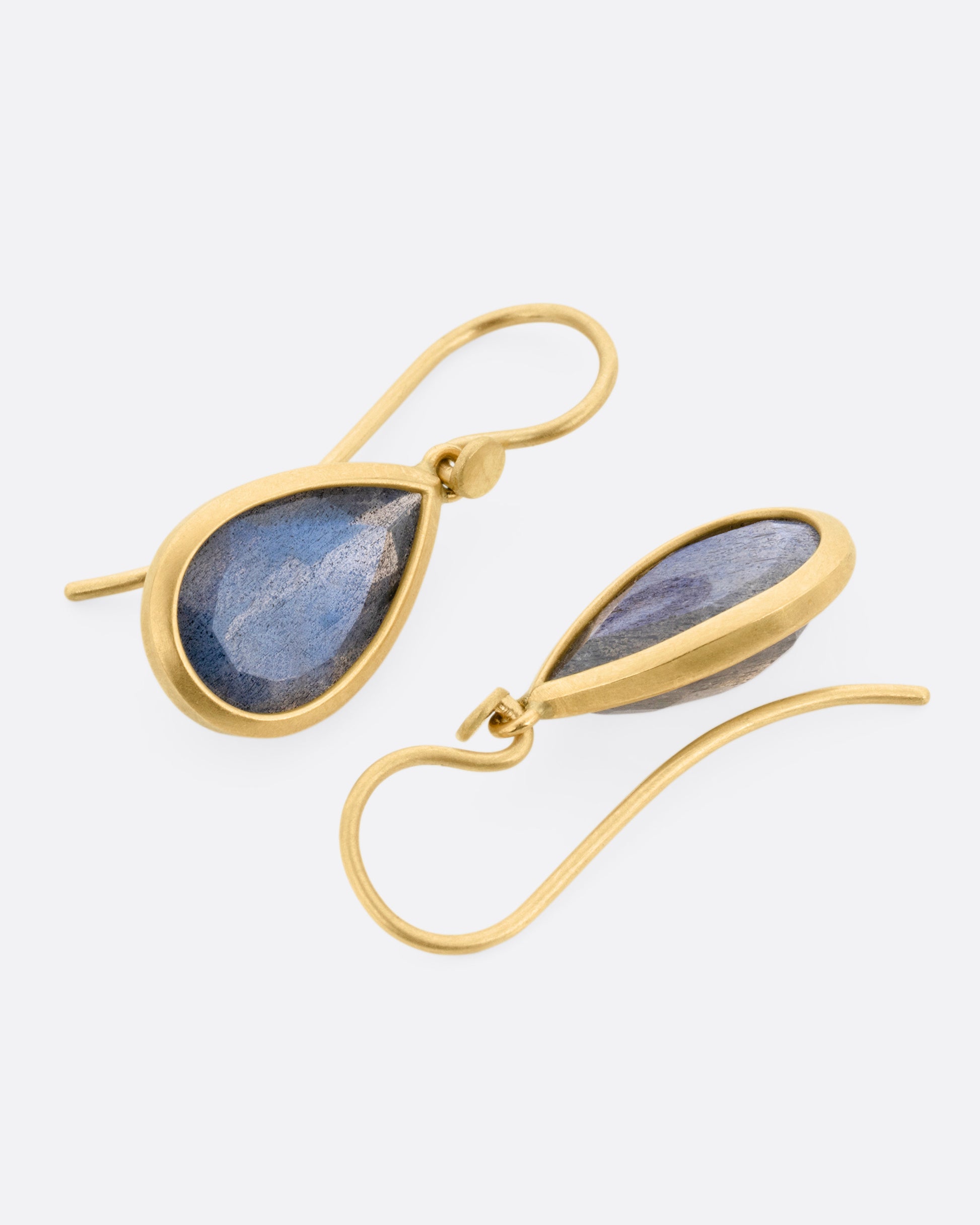 A pair of yellow gold earrings with labradorite teardrops, shown lying flat.