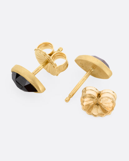 Yellow gold garnet navette stud earrings, the pair laid flat showing the posts and backs