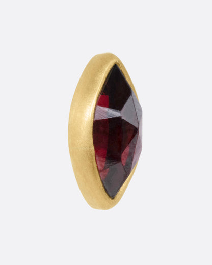 Yellow gold garnet navette stud earrings, close view of one stud showing the faceted garnet