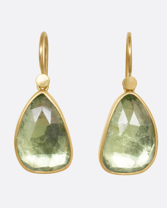 A pair of yellow gold drop earrings with pale green tourmalines, shown from the front.