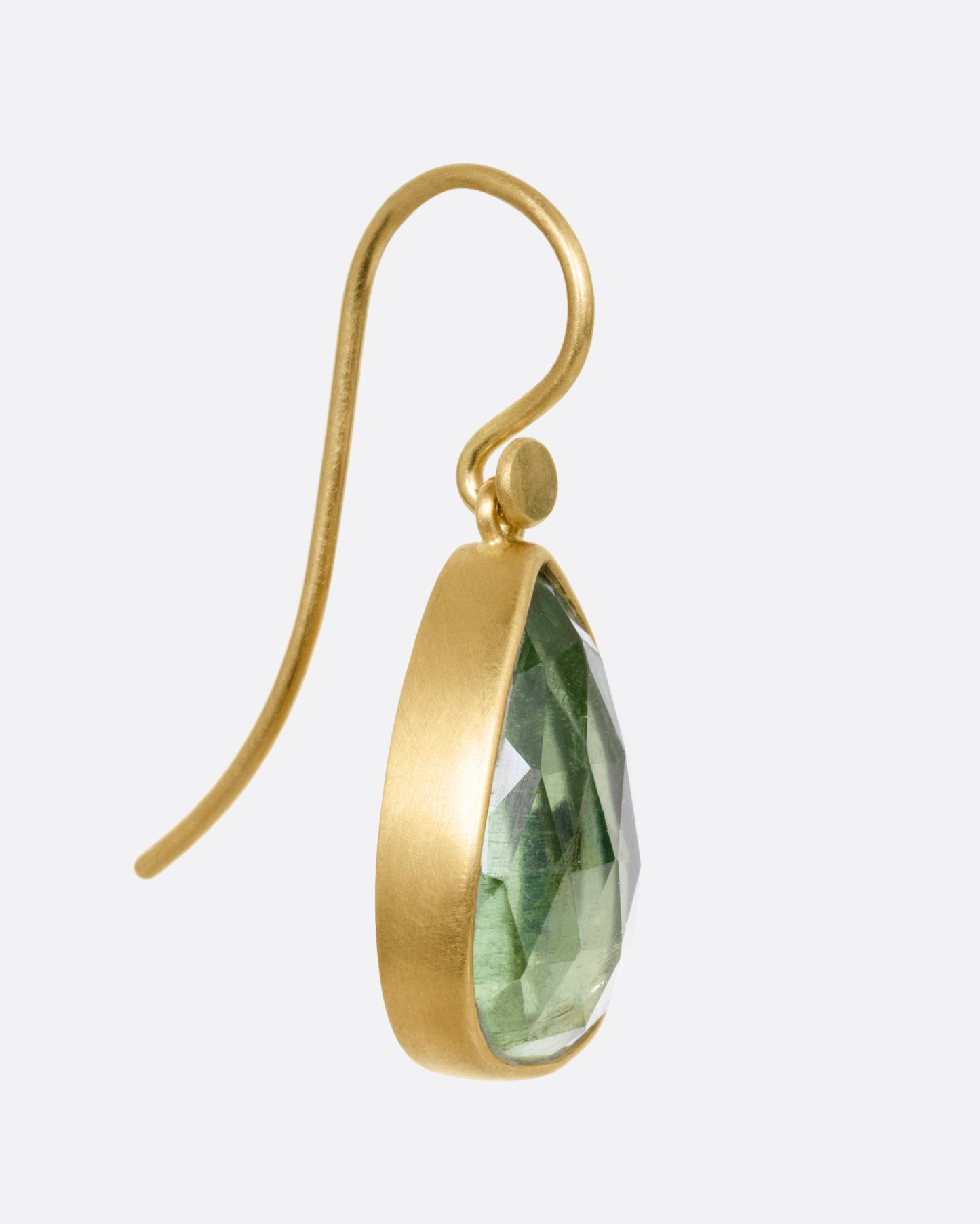 A yellow gold drop earring with a pale green tourmaline, shown from the side.