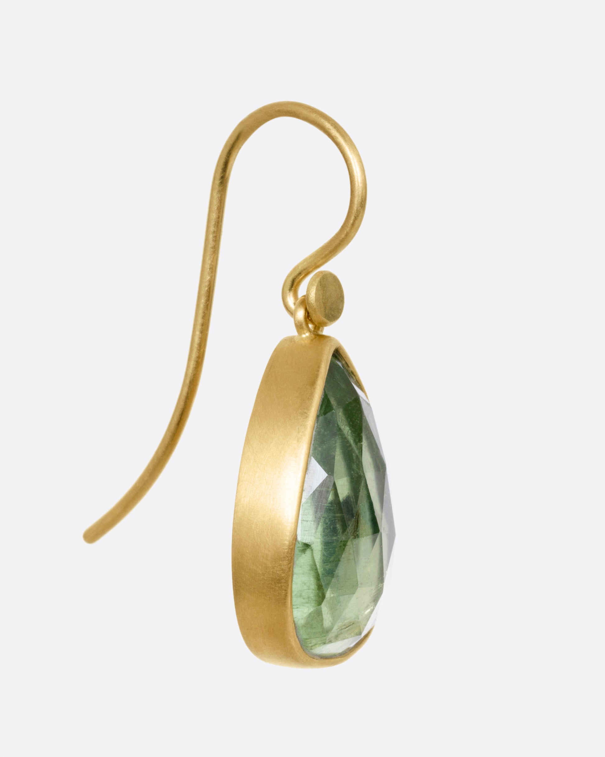 A yellow gold drop earring with a pale green tourmaline, shown from the side.