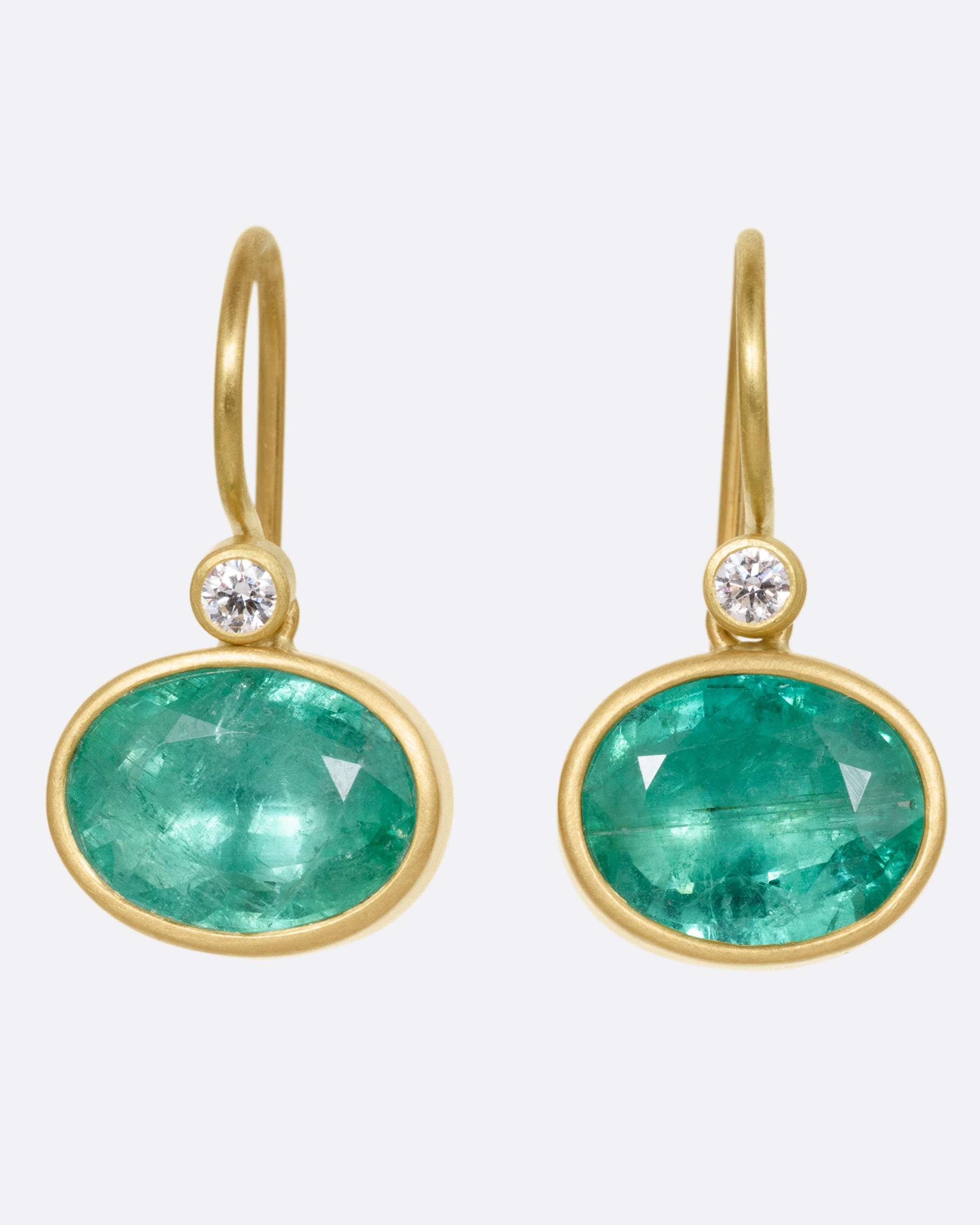 A pair of yellow gold drop earrings with Colombian emeralds and diamond accents, shown from the front.