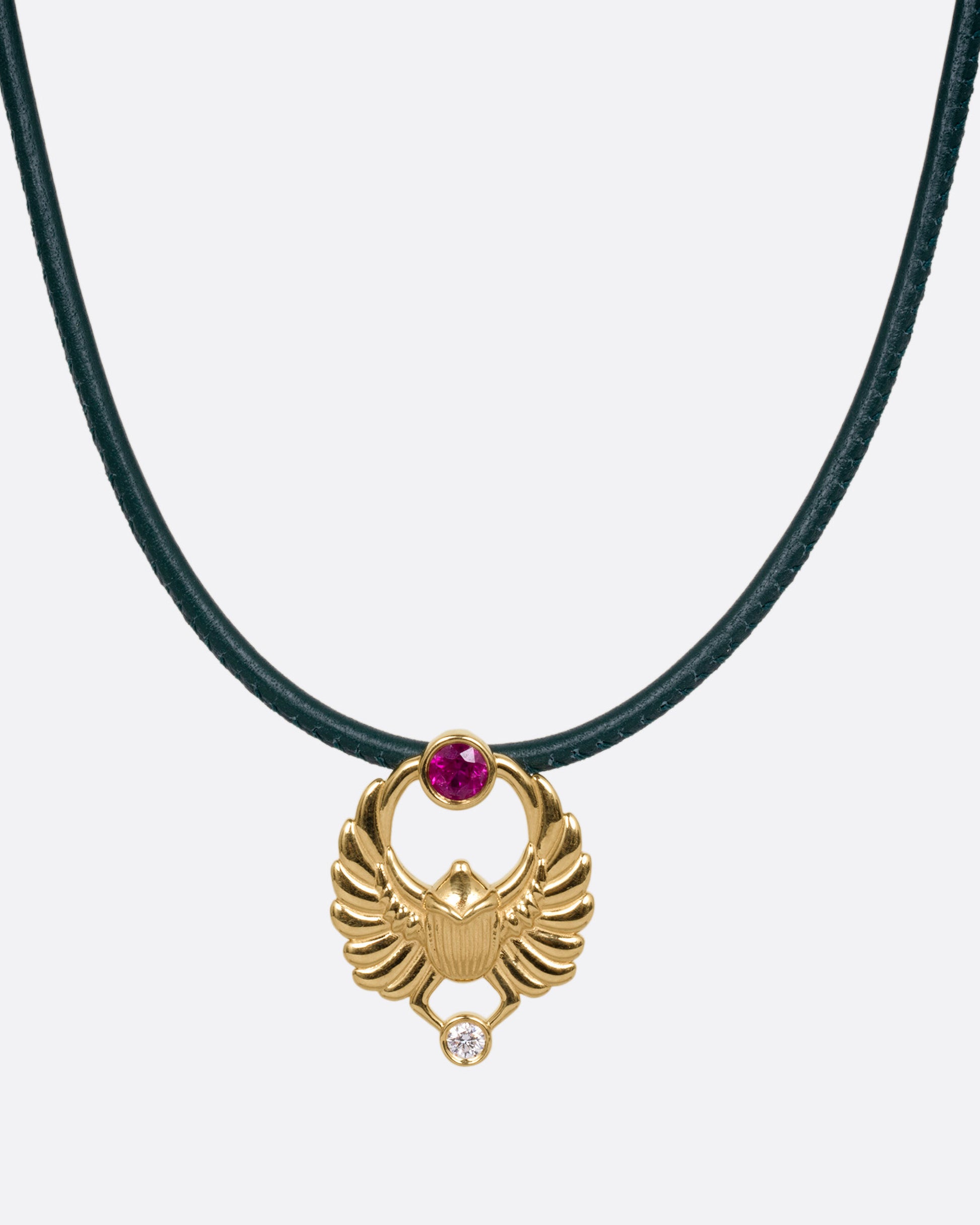 A yellow gold scarab pendant with a ruby and diamond, suspended from a green leather choker cord. Shown from the front.