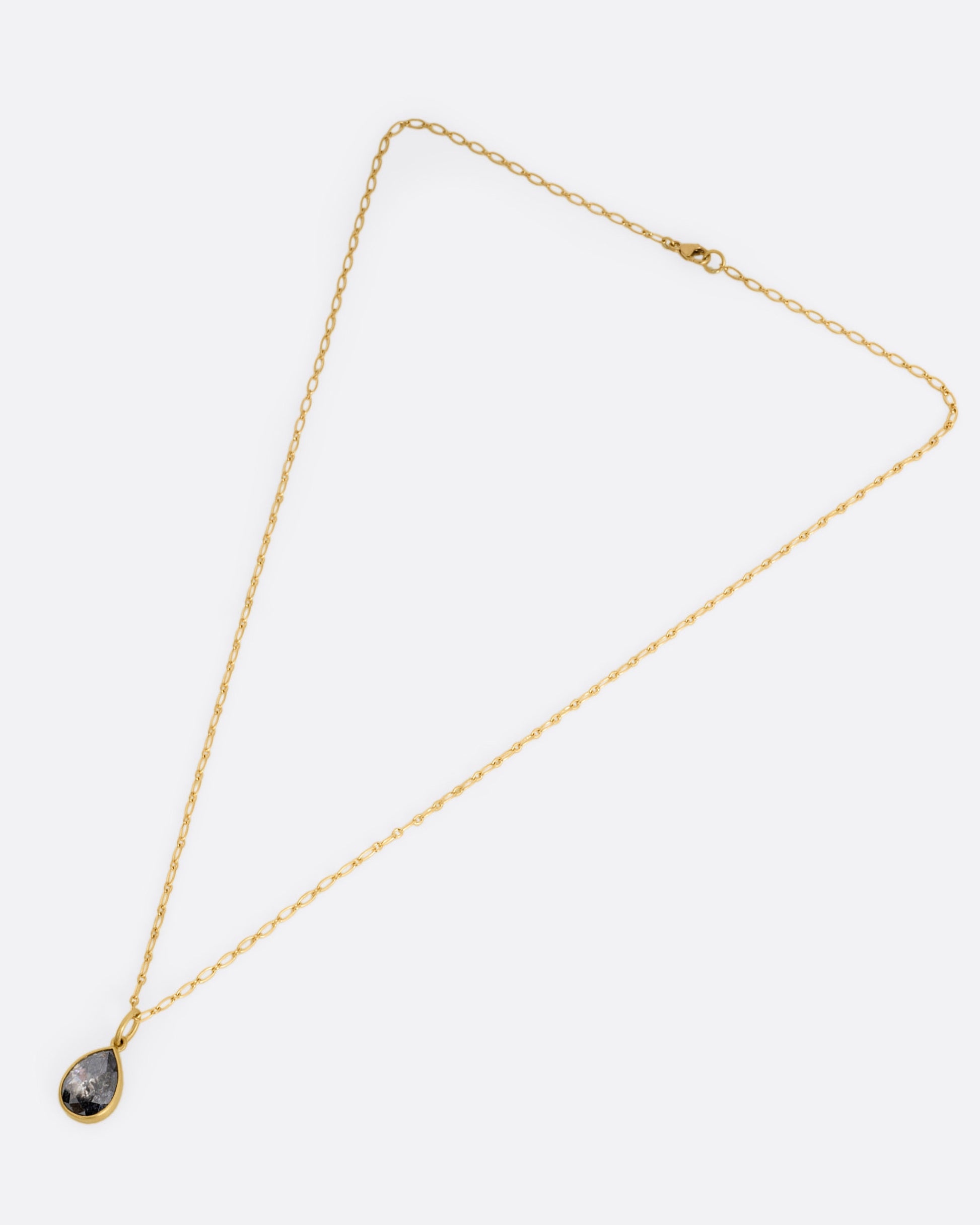 A yellow gold elongated link cable chain necklace with a teardrop shaped salt and pepper diamond, shown from the front.