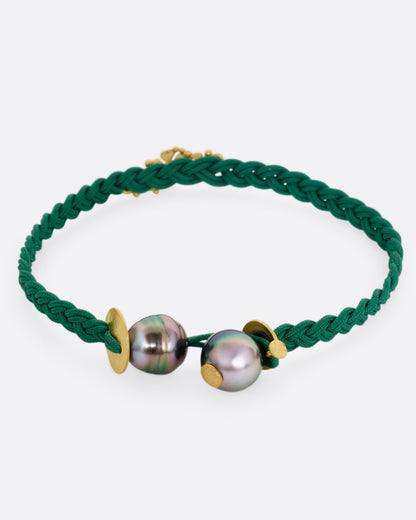 A braided green cord bracelet with a yellow gold cluster of diamond accented flowers and a Tahitian pearl toggle closure. Shown from the back.