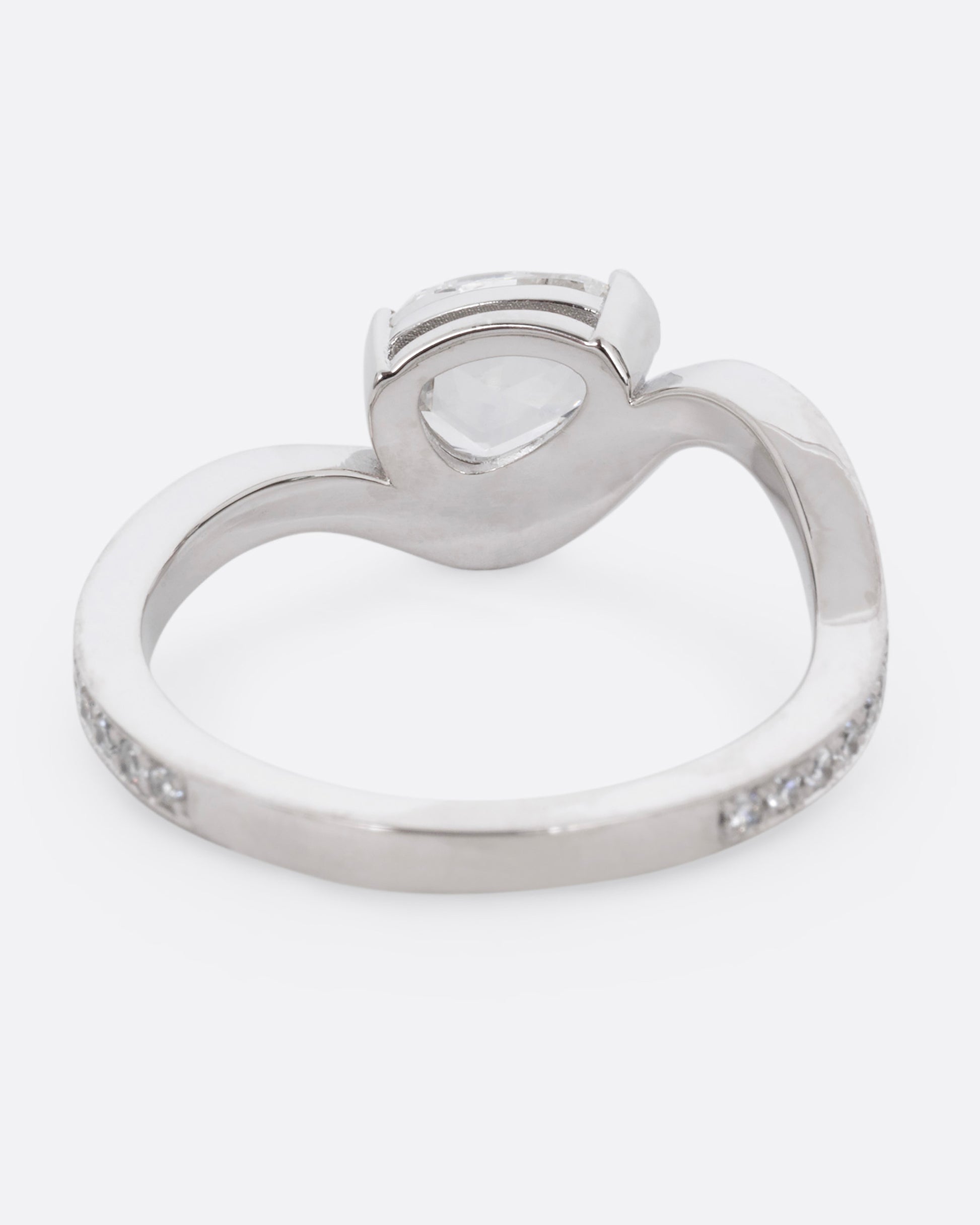 A diamond studded platinum ring with a wavy silhouette and a pear shaped rose cut diamond, shown from the back. 